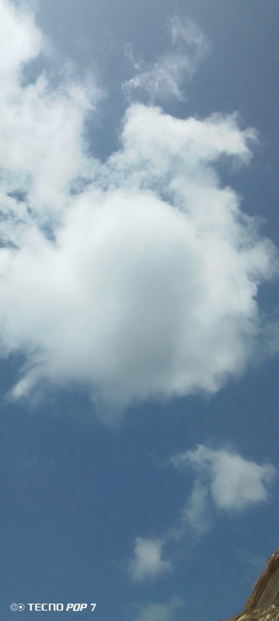 The image shows a daytime view of a blue sky with white clouds, including one large cumulus cloud in the center. The location is Pedro González, Venezuela. A small, light-colored portion of land, possibly a hill, is visible in the lower right corner. The words "TECNNO POP 7" are present in the bottom left corner of the frame. There are no people visible.