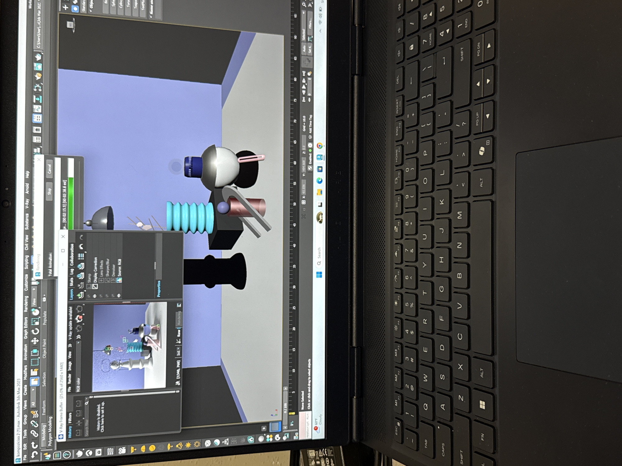 The image shows a laptop displaying a 3D modeling program, likely Autodesk 3ds Max, with a scene containing several geometric objects rendered with a light blue background. The objects include a sphere, cylinders, and a few flat shapes, arranged in an abstract composition. The laptop's keyboard and part of the trackpad are visible. The surrounding environment appears to be a dimly lit indoor space. There is no indication of the location being Yerevan, Armenia or any people.