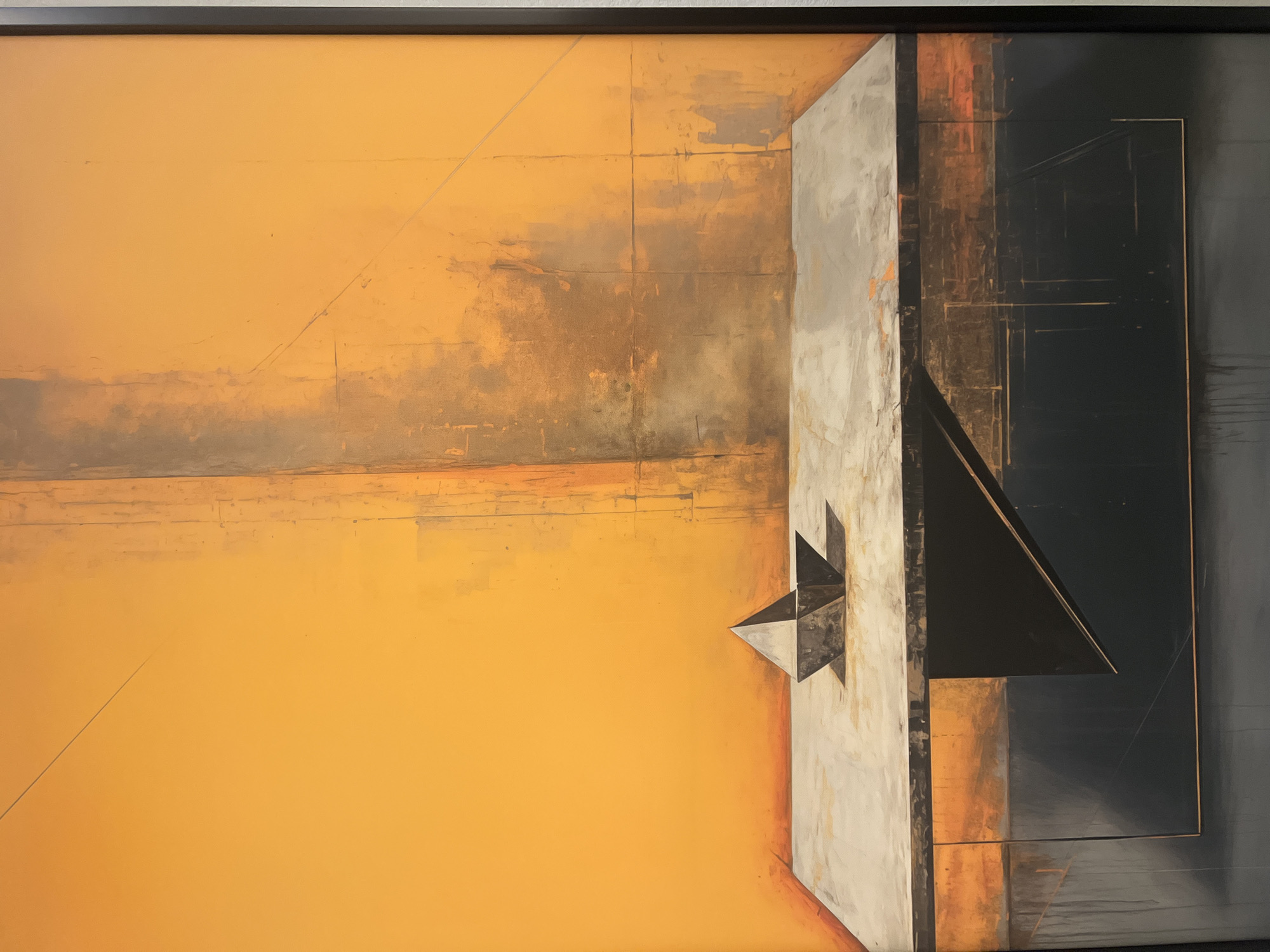 This is an image of an abstract painting featuring geometric shapes and a muted color palette. The primary colors are shades of orange, gray, and black, with some metallic or bronzed tones. In the foreground, a dark, faceted geometric object, possibly representing a stylized boat or prism, rests on a flat, textured surface that appears to be a table or platform. This surface is light gray with visible brushstrokes and subtle variations in tone. The background is dominated by a large expanse of bright, textured orange, with vertical streaks and subtle lines that suggest a distressed or aged wall. To the right and left of the orange background, there are darker, more muted areas with vertical textured elements. The bottom section of the painting is a dark, almost black area with sharp, geometric shapes and lines that create a sense of depth and shadow. The painting is framed by a thin black border. This artwork is displayed within a gallery space, as indicated by the lighting and the presence of a thin black frame around the canvas. The artwork is not located in the city of Saint Petersburg, Russia.
