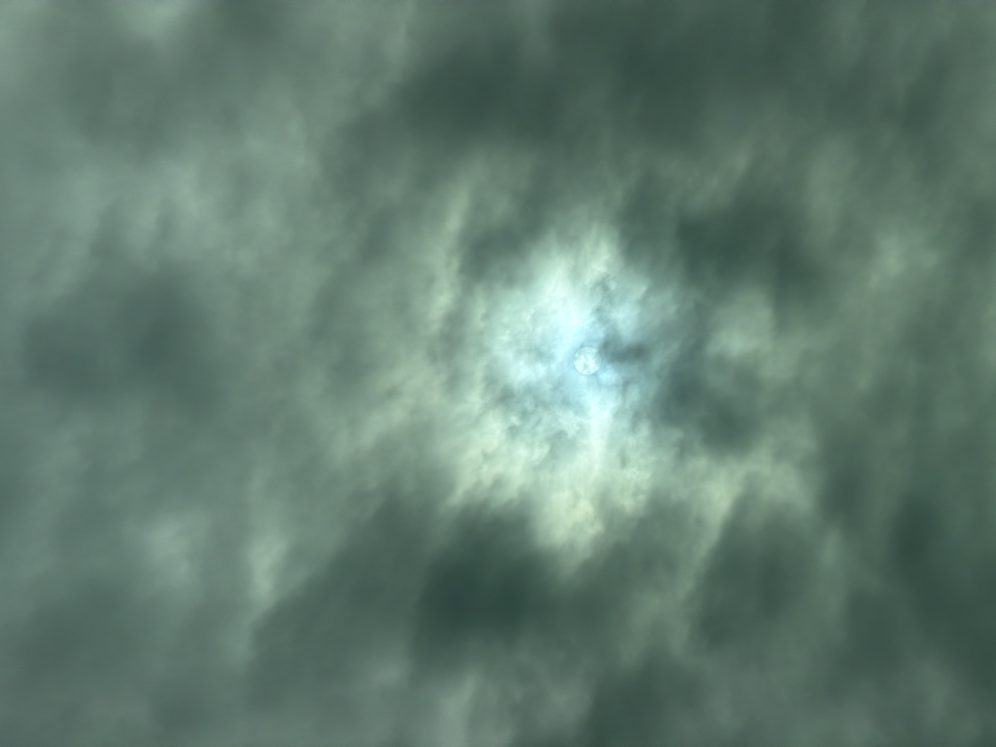 The image shows a cloudy sky with a bright, diffused light source in the center, possibly the sun. The clouds are dark and appear to be moving, creating a sense of depth and movement. The overall color palette is dominated by shades of grey and green, with a bluish tint around the light source. There are no discernible objects, people, or actions visible in the image. The scene appears to be an outdoor shot, likely taken during the daytime. Without additional information or context, it is not possible to determine the specific location within Dmitrovskoye, Russia, or any other environmental details.