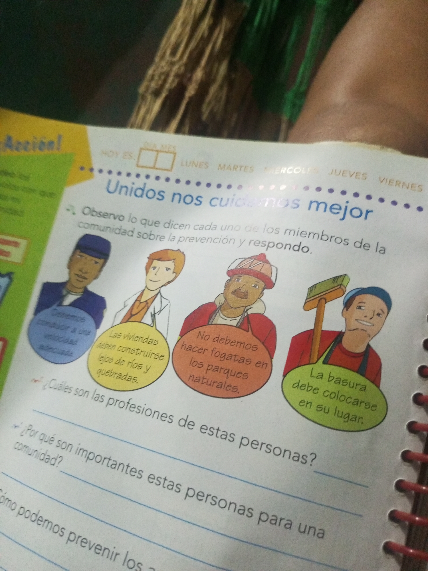 This image depicts a page from a workbook or educational material for children, featuring illustrations and text related to community safety and the importance of different professions. The overall scene is a colorful, two-dimensional illustration on a white background. At the top, there is a title in large blue font that reads "Unidos nos cuidamos mejor" (Together we take care of ourselves better). Above this, there are placeholders for "HOY ES" (Today is) followed by boxes for the day and month, and a list of days of the week: LUNES, MARTES, MIERCOLES, JUEVES, VIERNES. The central part of the image displays four illustrated characters, each with a speech bubble containing advice or statements related to community well-being. The first character on the left, dressed in a blue uniform and cap, appears to be a police officer or security guard. His speech bubble says, "Debemos conducir a una velocidad adecuada" (We must drive at an appropriate speed). The second character, in an orange shirt and white coat, resembles a doctor or healthcare professional. His speech bubble states, "Las viviendas deben construirse lejos de ríos y quebradas" (Dwellings must be built far from rivers and ravines). The third character, wearing a red hat with orange trim and a red jacket, looks like a firefighter. His speech bubble reads, "No debemos hacer fogatas en parques naturales" (We must not make bonfires in natural parks). The fourth character, in a red shirt and blue apron, is holding a broom, suggesting he is a sanitation worker or cleaner. His speech bubble says, "La basura debe colocarse en su lugar" (Trash must be placed in its place). Below the illustrations, there are questions for the students to answer, indicated by bullet points. The first question is partially visible: "¿Cuáles son las profesiones de esta personas?" (What are the professions of these people?). The subsequent question is "Por qué son importantes estas personas para la comunidad?" (Why are these people important to the community?). Another partially visible line reads, "Cómo podemos prevenir los..." (How can we prevent the...). The image does not contain any specific visual elements that would allow for the identification of its location within the city of La Tagua, Venezuela. The context is educational and generic, focusing on common community safety themes. The surrounding environment is out of focus and appears to be a domestic or classroom setting, with a brown, woven material visible