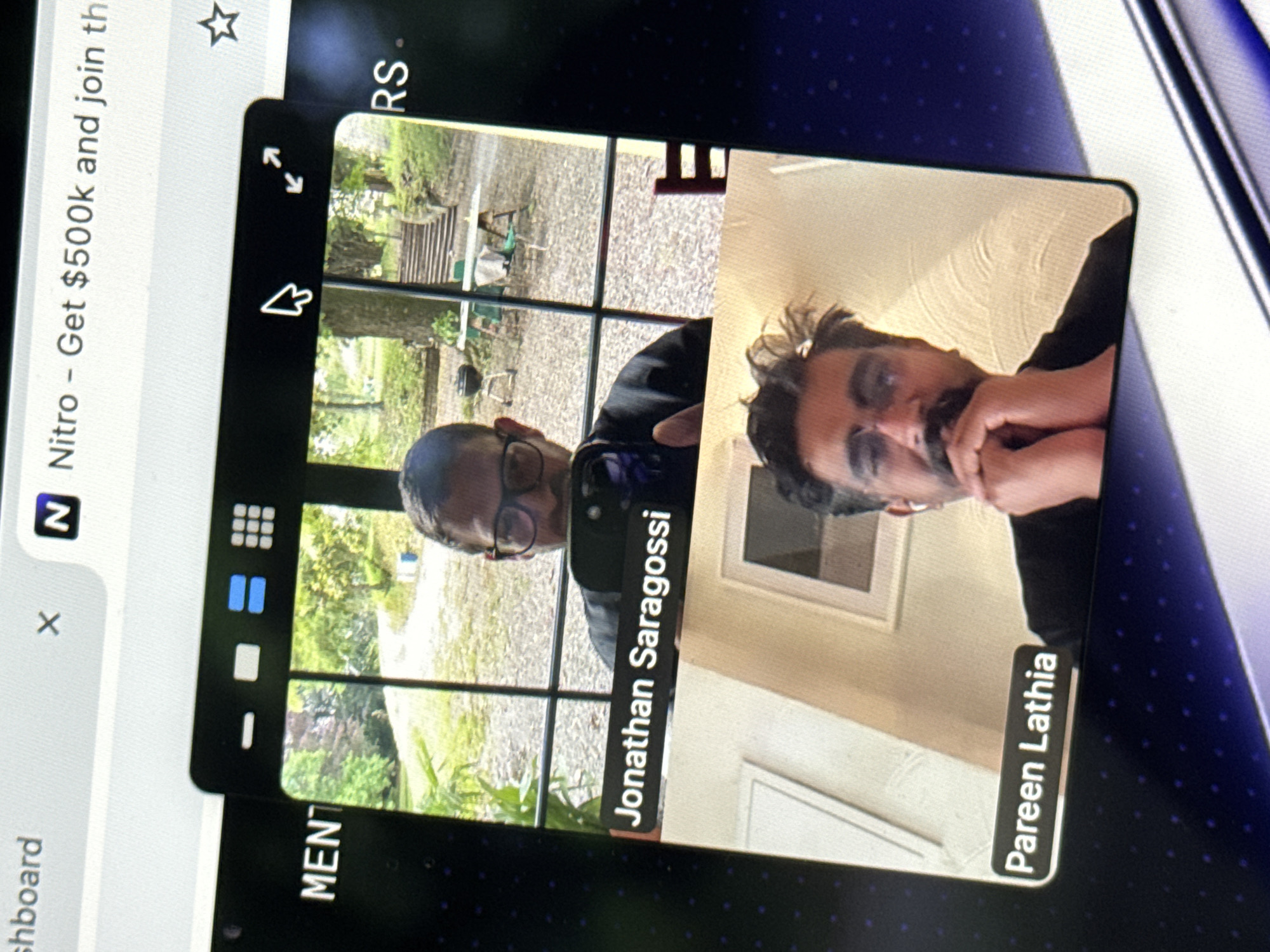 The image shows a screenshot of a video conference call. In the top frame, a man with glasses is visible. A label below his frame reads "Jonathan Saragossi". In the bottom frame, another man with glasses and a mustache is visible. A label below his frame reads "Pareen Lathia". The video conference window is overlaid on a computer screen displaying a browser tab with the title "Nitro - Get $500k and join th". The user's computer screen displays a background with a dark blue, speckled pattern. There are no elements in the image that suggest a specific location in the city of Erba, Italy.