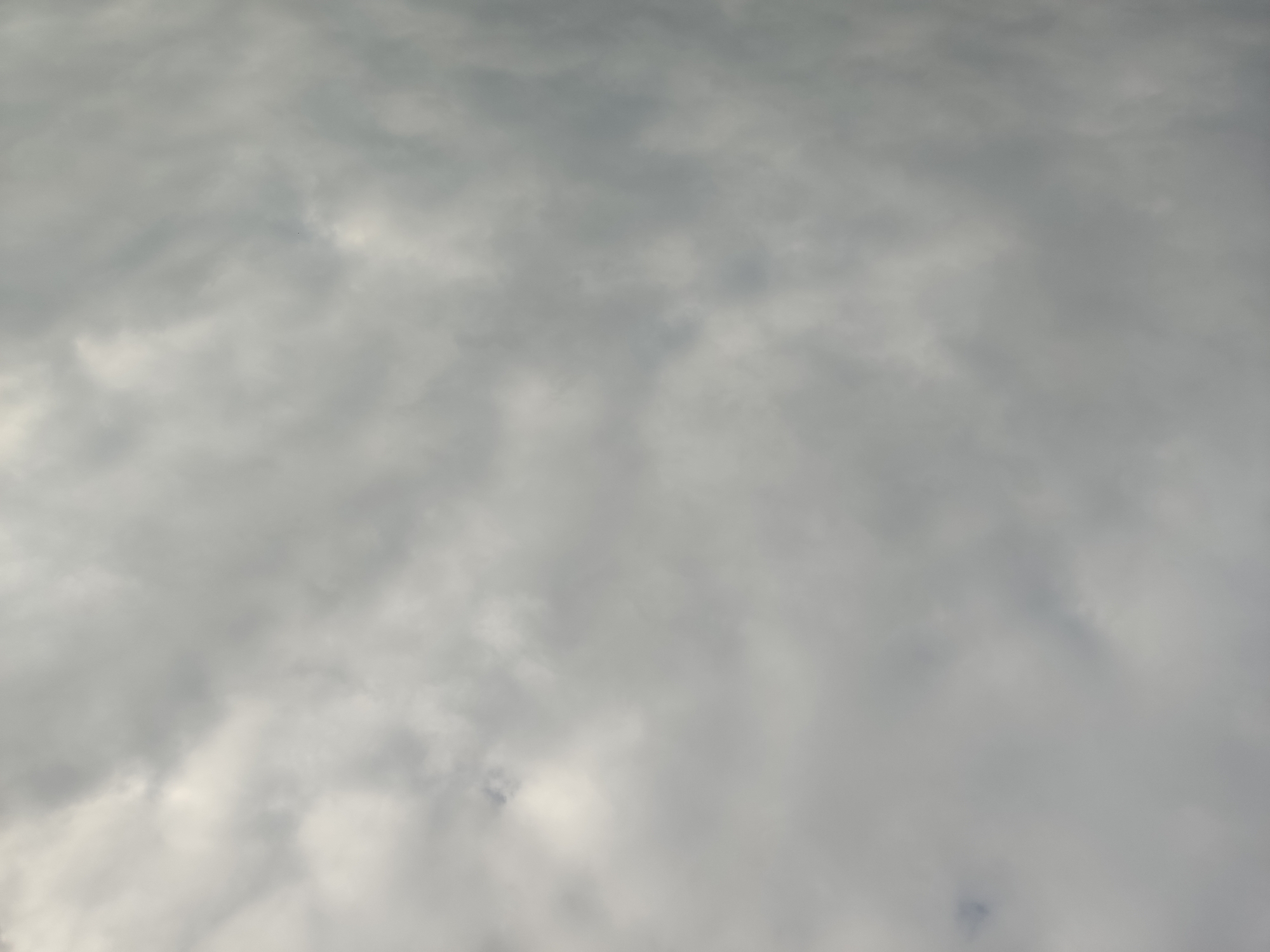 A wide shot shows a sky filled with gray and white clouds. The clouds are dense and appear to be covering the entire sky. There is no visible sun, and the lighting suggests an overcast day. The image is devoid of any structures, people, or objects. The location is described as Unknown, Unknown.
