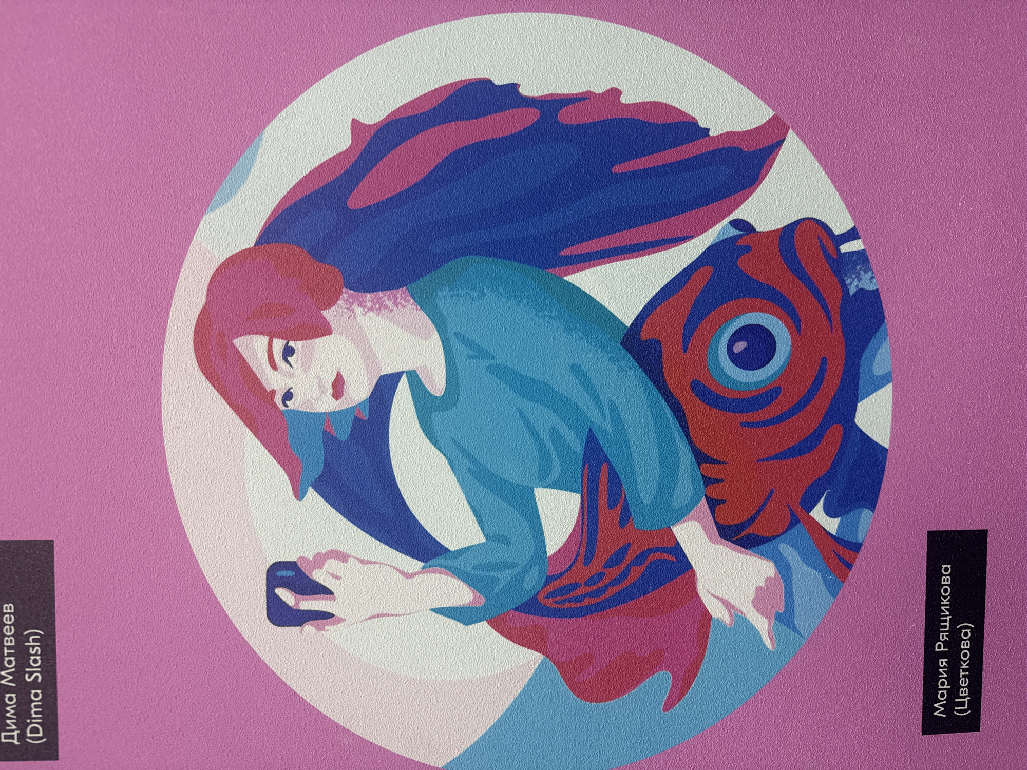 The image depicts a woman looking down at a phone in her hand, positioned in front of a stylized fish with large fins. The woman has red hair and wears a blue shirt. The fish is rendered in shades of blue and red. The background is a circular white field set against a pink background. To the left and right, there are black vertical boxes containing white text. The text on the left box reads "Дима Матвеев (Dima Slash)". The text on the right box reads "Мария Рящикова (Цветкова)". The text suggests the image is related to an exhibition in Saint Petersburg, Russia.