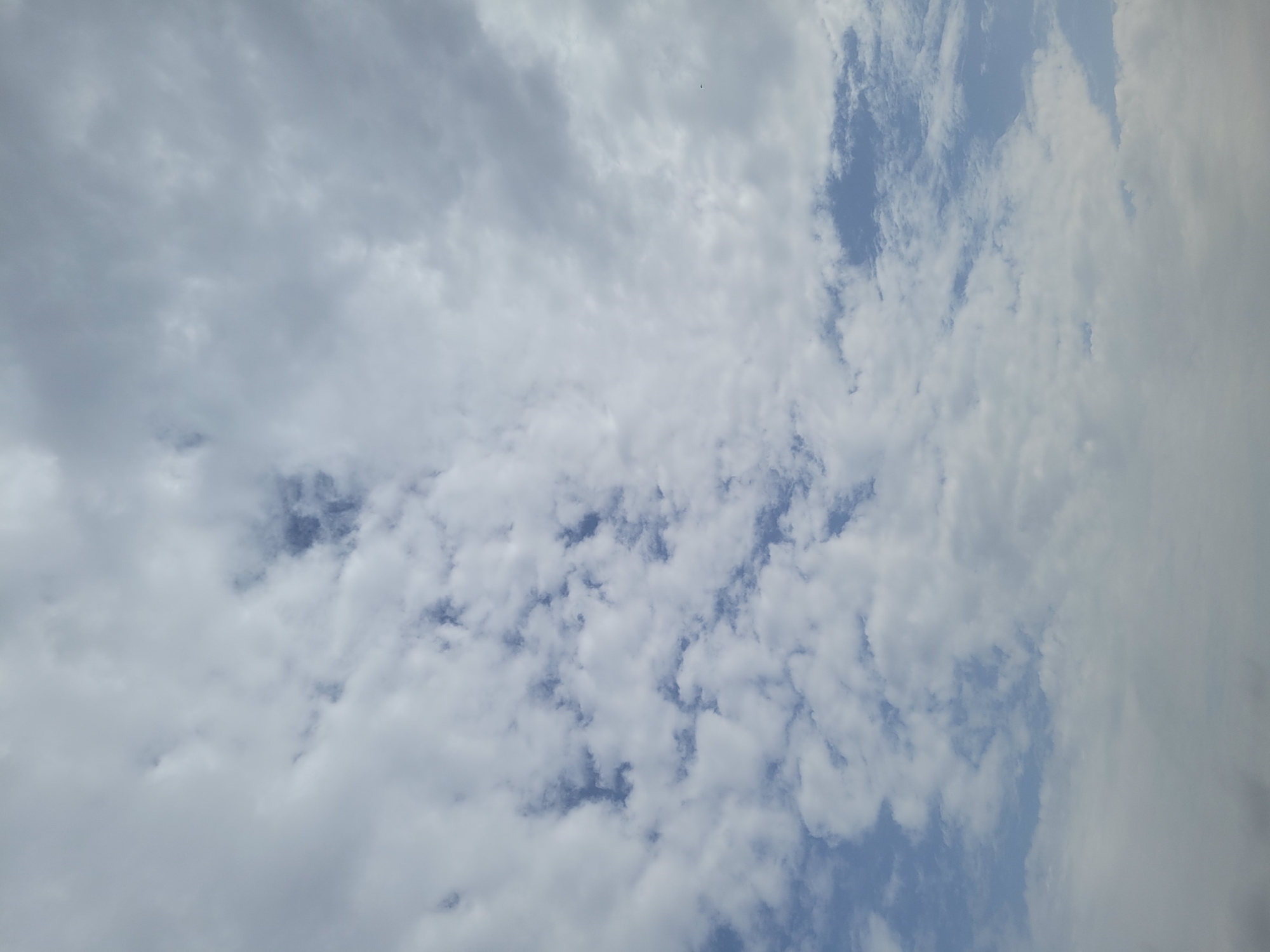 The image shows a sky filled with clouds. There are patches of blue sky visible between the clouds. The clouds are a mix of white and gray. The image was taken in Jos, Nigeria.