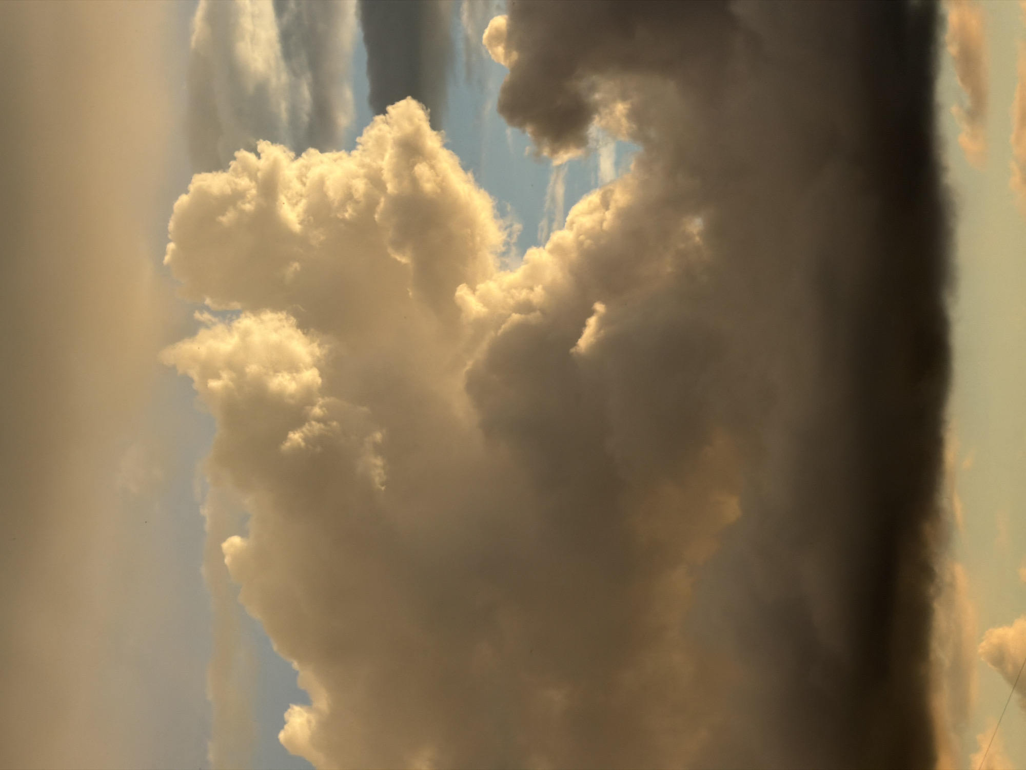 The image shows a large cumulonimbus cloud formation in the sky. The cloud on the left is bright and billowy, while the one on the right is darker and appears more ominous. Patches of blue sky are visible between the clouds. The location is likely Moscow, Russia, but it is impossible to confirm this without additional context.