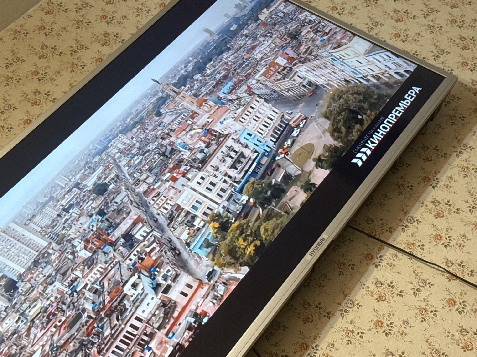 A Hyundai television displays an aerial view of Havana, Cuba. The screen displays the words "KINOPREMYERA" in Cyrillic, which translates to "Movie Premiere." The television sits on a surface covered with a floral patterned fabric. There is no indication that this image is of Mytishchi, Russia.