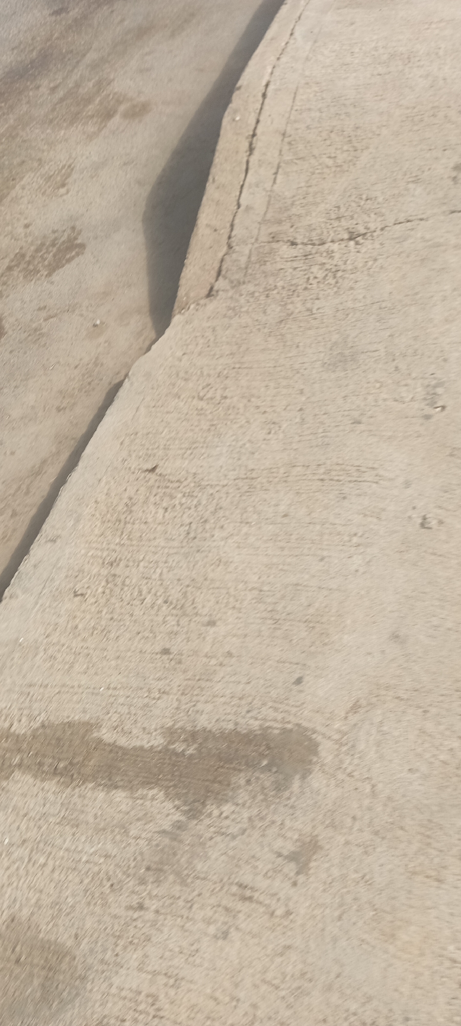 The image shows a close-up view of a concrete surface. The concrete appears to be weathered and stained in places. The image includes a vertical ledge. The location is presumed to be in the city of Bukuru, Nigeria. No people, other subjects, objects, actions, or interactions are observed.