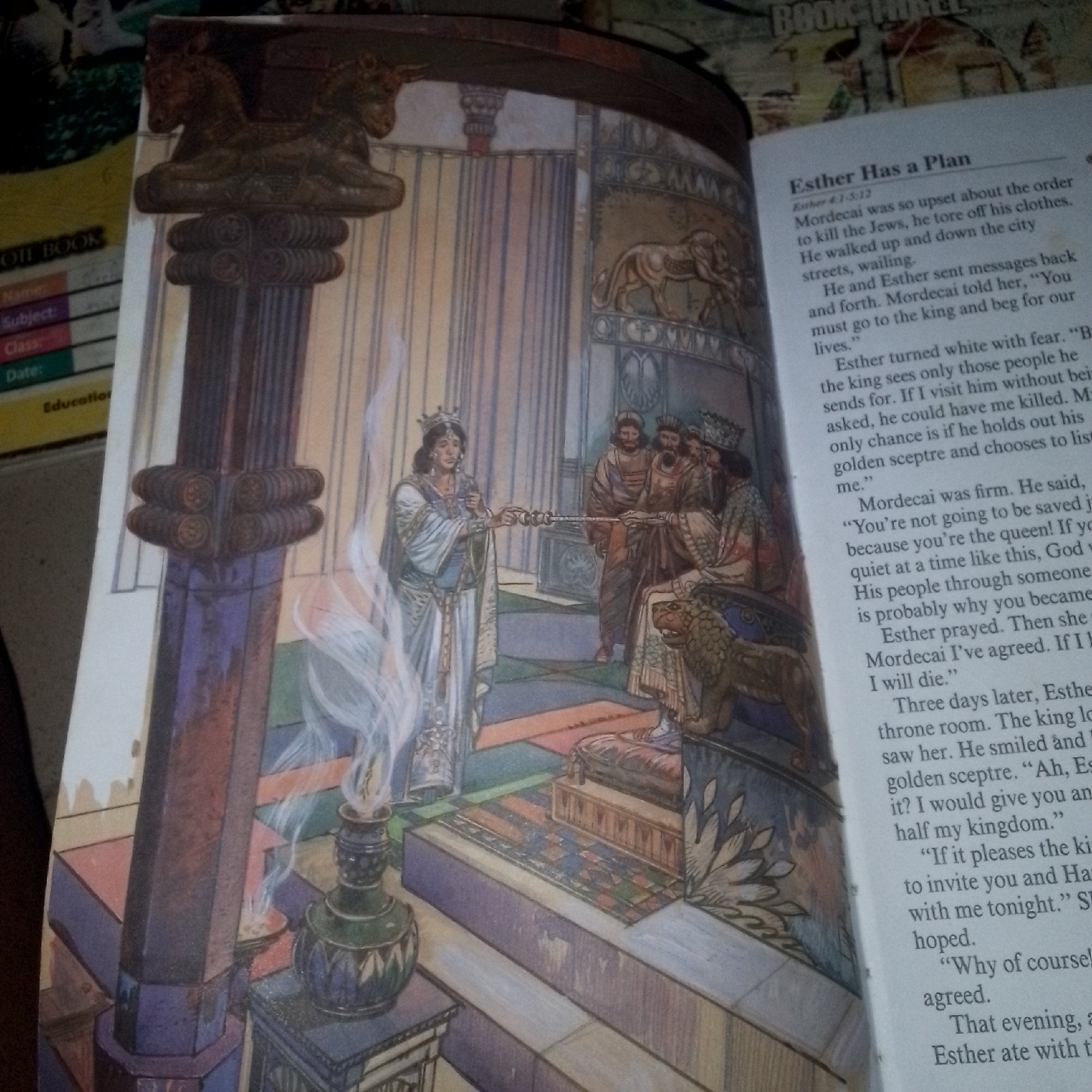 The image shows an open book with an illustration on the left page and text on the right page. The illustration depicts a scene in what appears to be a royal court or palace. In the foreground, a large, ornate pillar stands to the left. The central figure is a woman wearing a crown and a flowing white and blue robe, holding a scepter. She is facing a group of men seated on a raised platform. One of the seated men is positioned on a throne-like structure adorned with a lion. Other men are standing behind the seated figures. The background features tall, striped curtains and decorative elements. Smoke or mist is rising from a small, green vase-like object on the lower left.
The text on the right page is a story titled "Esther Has a Plan" with a reference to "Esther 4:1-5:12". The text describes events involving characters named Mordecai and Esther, recounting Mordecai's distress and a conversation with Esther. The environment depicted in the illustration is likely within a historical or biblical setting, characterized by opulent architecture and attire. The image appears to be a page from a children's book or a religious publication.