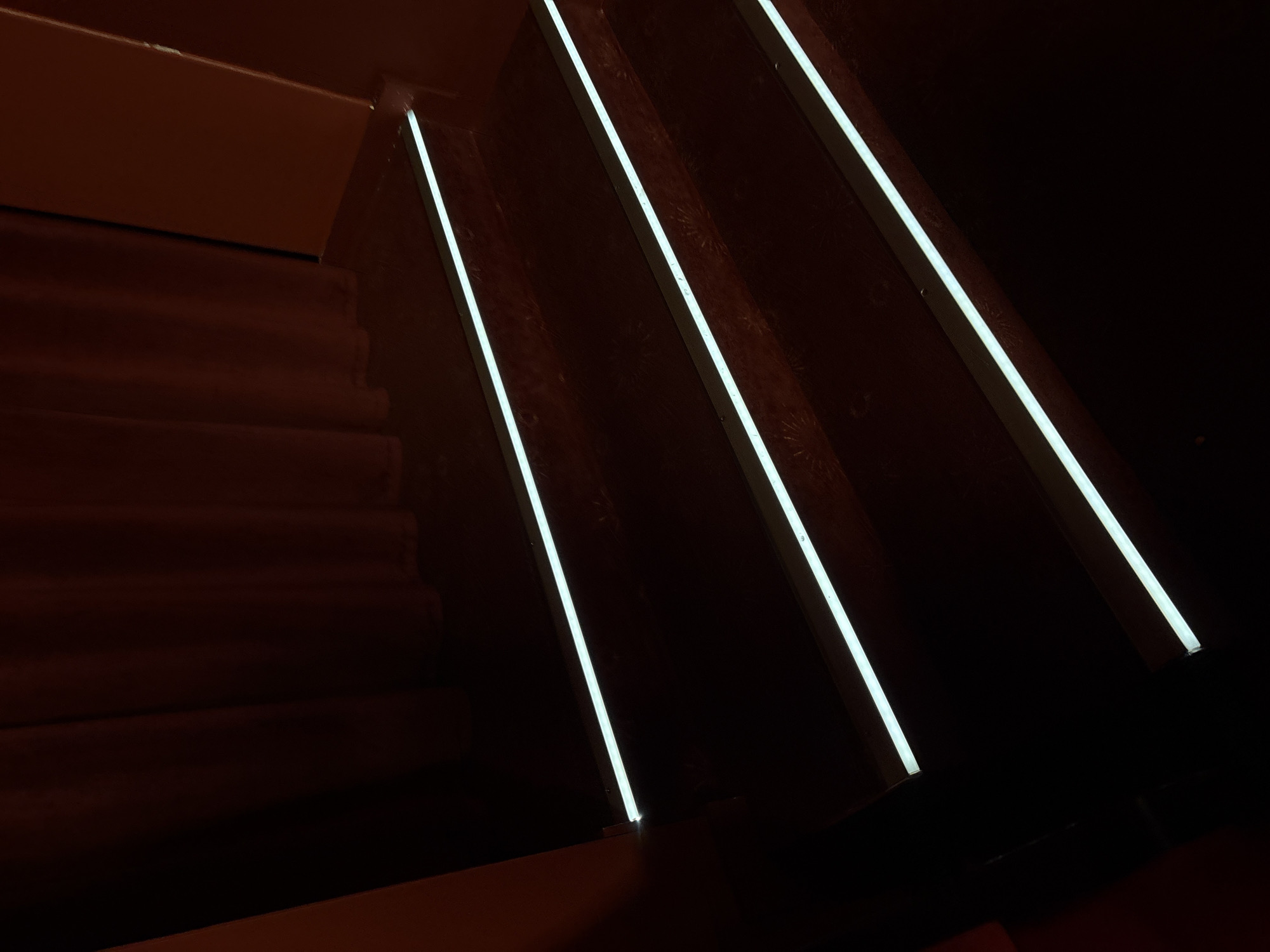 A dimly lit staircase with illuminated edges, constructed of wood. The scene is in Minsk, Belarus.