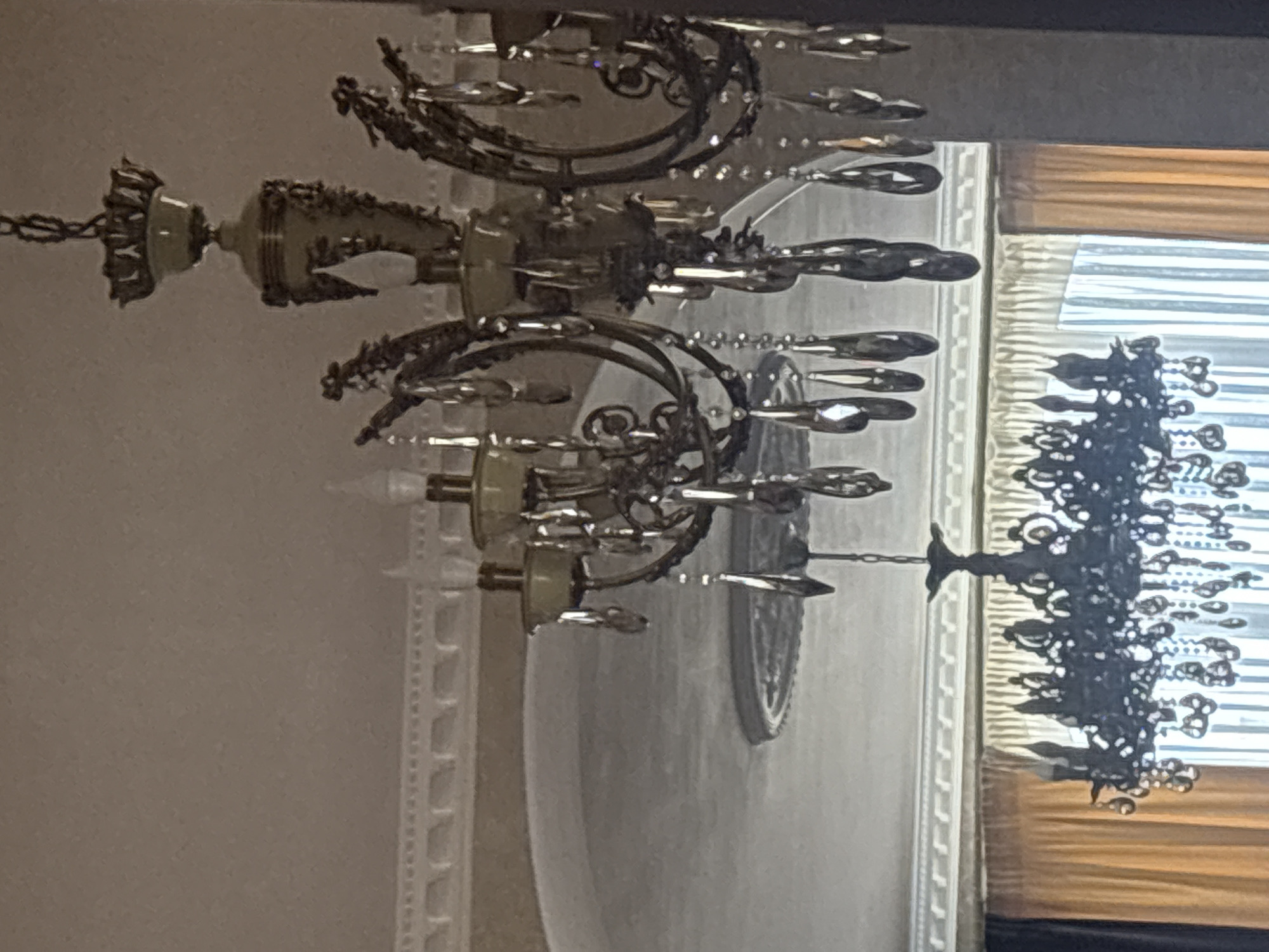 The image shows an interior scene with two chandeliers hanging from the ceiling. The ceiling has decorative molding. In the background, there are curtains and an arched doorway. There are no people visible in the image. The image is taken from a low angle, looking upwards at the chandeliers. The location of the scene is not specified in the image or its metadata. Therefore, it is not possible to determine the location in the city of Georgiyevsk, Russia.