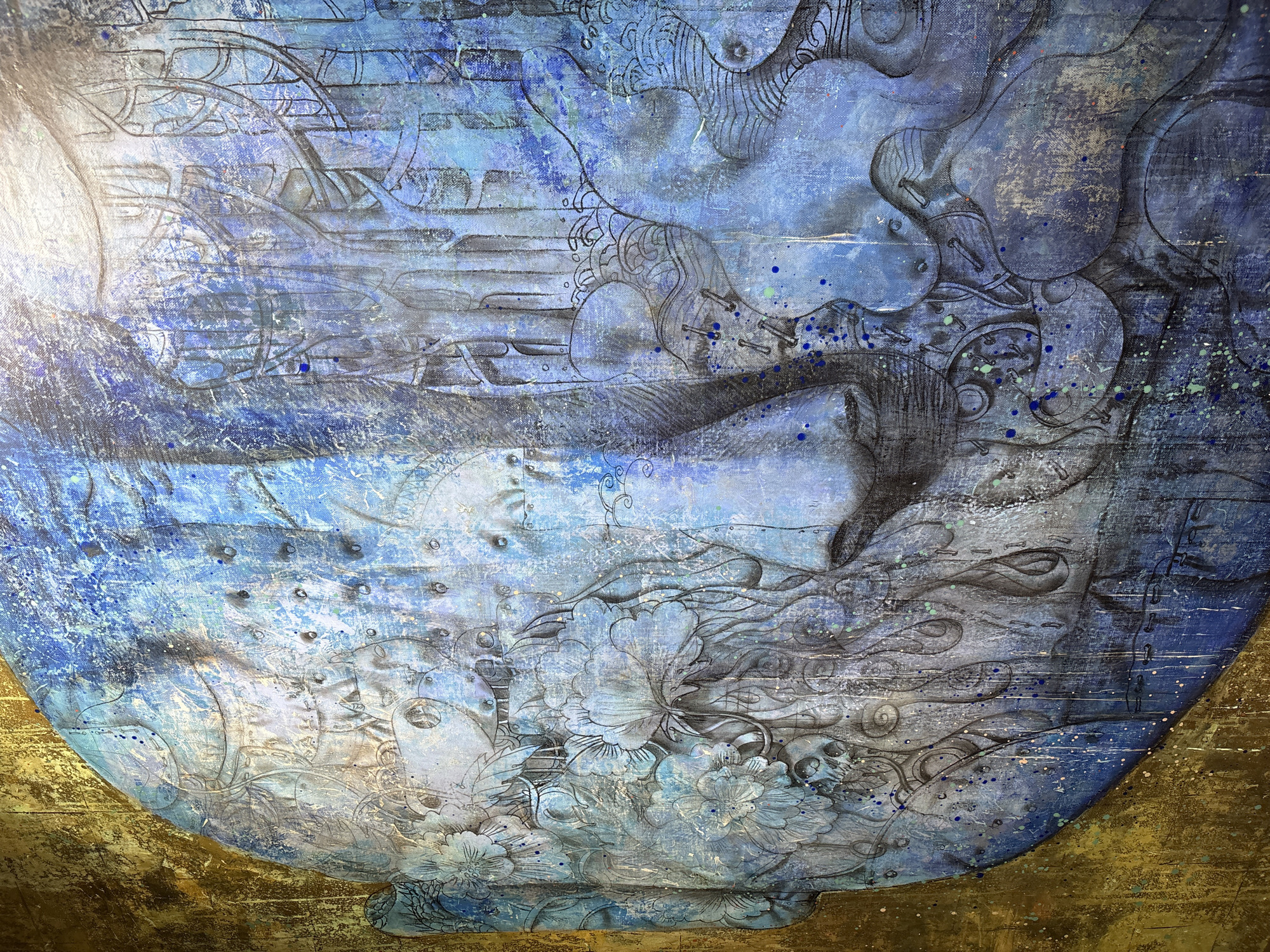 The image is a detail of a painted artwork depicting a round, vase-like form dominating the composition. The vase shape is rendered in shades of blue, ranging from light to deep navy, with areas of grey and white providing highlights and contrast. A floral pattern decorates the lower portion of the vase, featuring blooms with detailed line work. Lines and intricate details also seem to represent a city, but the city is not Irkutsk, Russia. The texture appears rough, with splatters and streaks of paint. The vase seems to rest on a golden surface, which appears textured and aged.