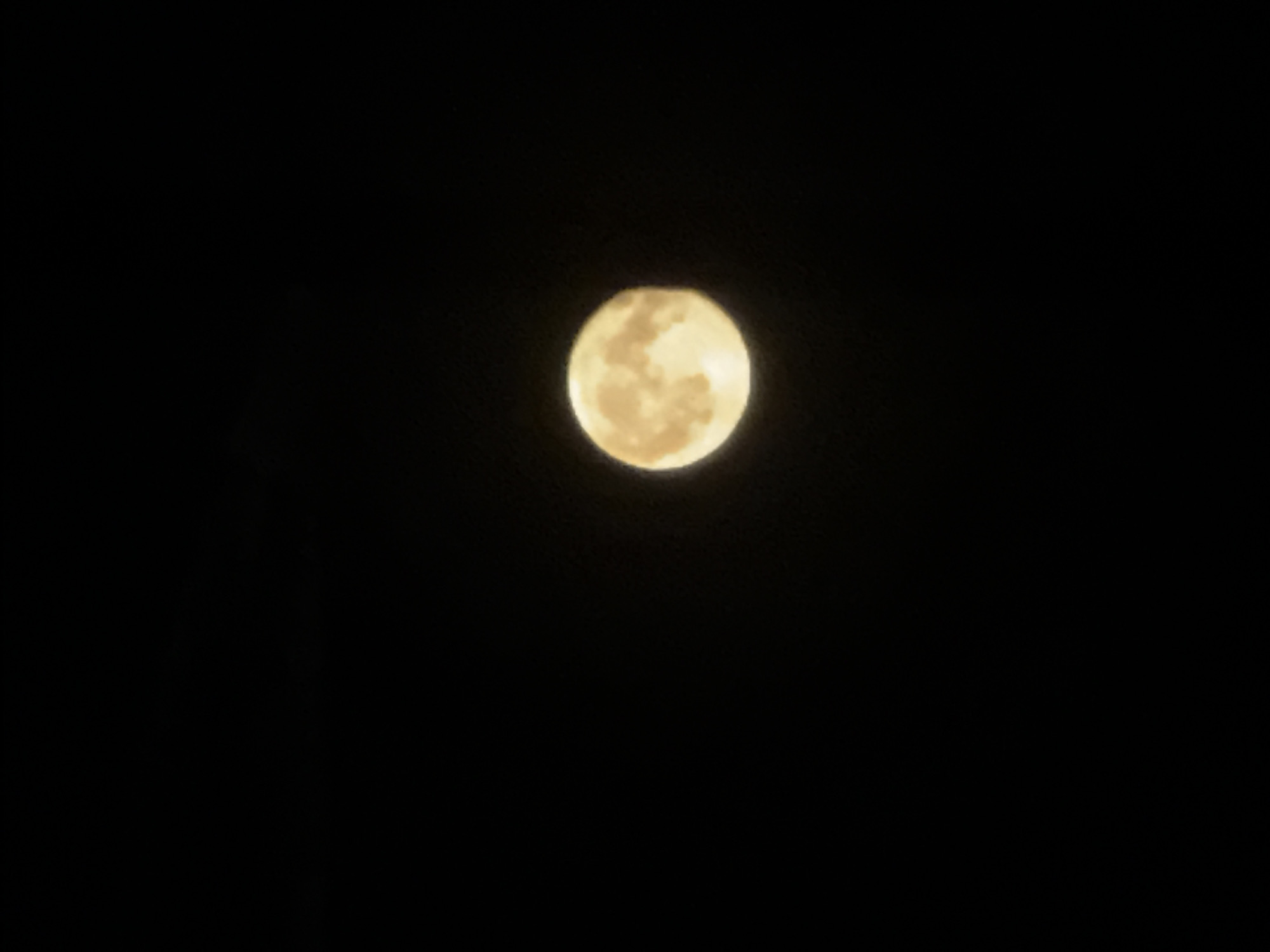The image shows a full moon against a black sky. The moon is a pale yellow color and appears to have some craters visible on its surface. The sky is completely dark, indicating that it is nighttime. There are no other objects or details visible in the image. The location in the city of Baryshevo, Russia is not discernible from the image.