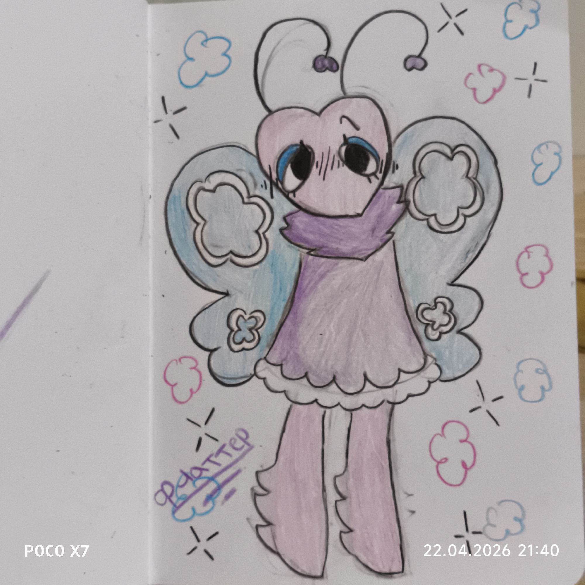 A colorful, hand-drawn character resembling a butterfly or moth is depicted on a white sheet of paper, likely from a sketchbook, in Chaikovsky, Russia. The character has a light pink heart-shaped head with large, wide black eyes featuring blue accents, and slightly furrowed brows suggesting a shy or melancholic expression. It wears a light purple dress with a ruffled white hem and a darker purple frilly collar or scarf around its neck. Two large, light blue wings with intricate white clover-like patterns extend from its back. Its antennae curl upwards, topped with small purple heart shapes. The character stands on two thick, light pink legs that are ruffled at the bottom.
The background around the character is adorned with small, irregularly shaped clouds in light blue and pink, interspersed with black sparkle symbols.
Visible text includes "POCO X7" at the bottom left, and a date and time stamp "22.04.2026 21:40" at the bottom right. A signature or name, "Фаттер," is written in purple on the left side of the paper, near the character's legs, underlined by purple lines. The drawing has a whimsical, cartoonish style, rendered with colored pencils or crayons.