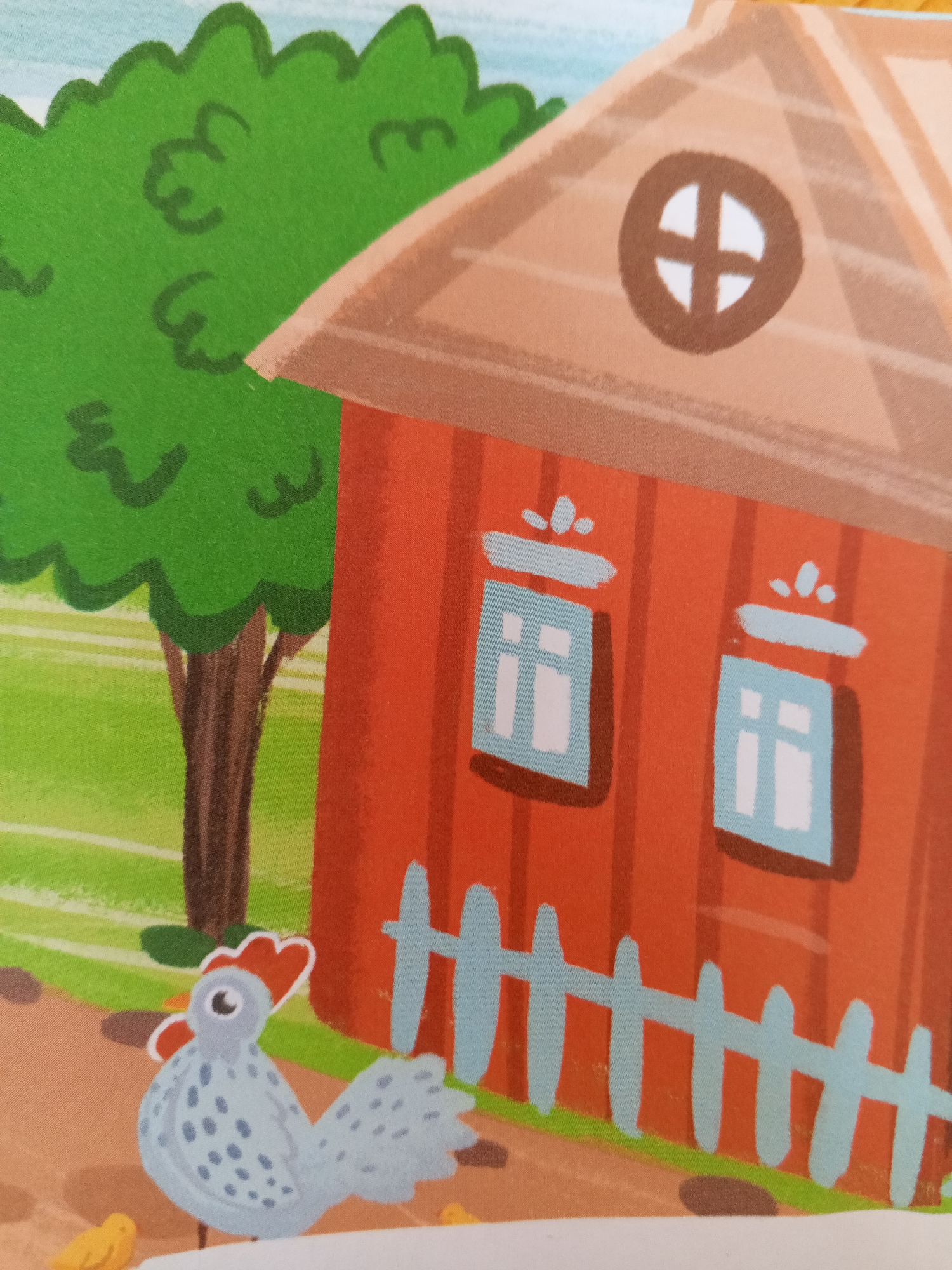 The image depicts a stylized, cartoonish illustration of a farm scene. A red barn with a brown roof and a circular window with a cross shape is prominent. In front of the barn, a light blue fence with white posts encloses an area. To the left of the barn, a green, bushy tree with a brown trunk stands in a grassy area. In the foreground, a light blue chicken with gray spots and red accents is shown, and a yellow chick is partially visible to its left. The overall scene suggests a rural or farm setting, likely a children's illustration. There is no information or visual evidence to suggest this image is located in the city of Chistopol, Russia.