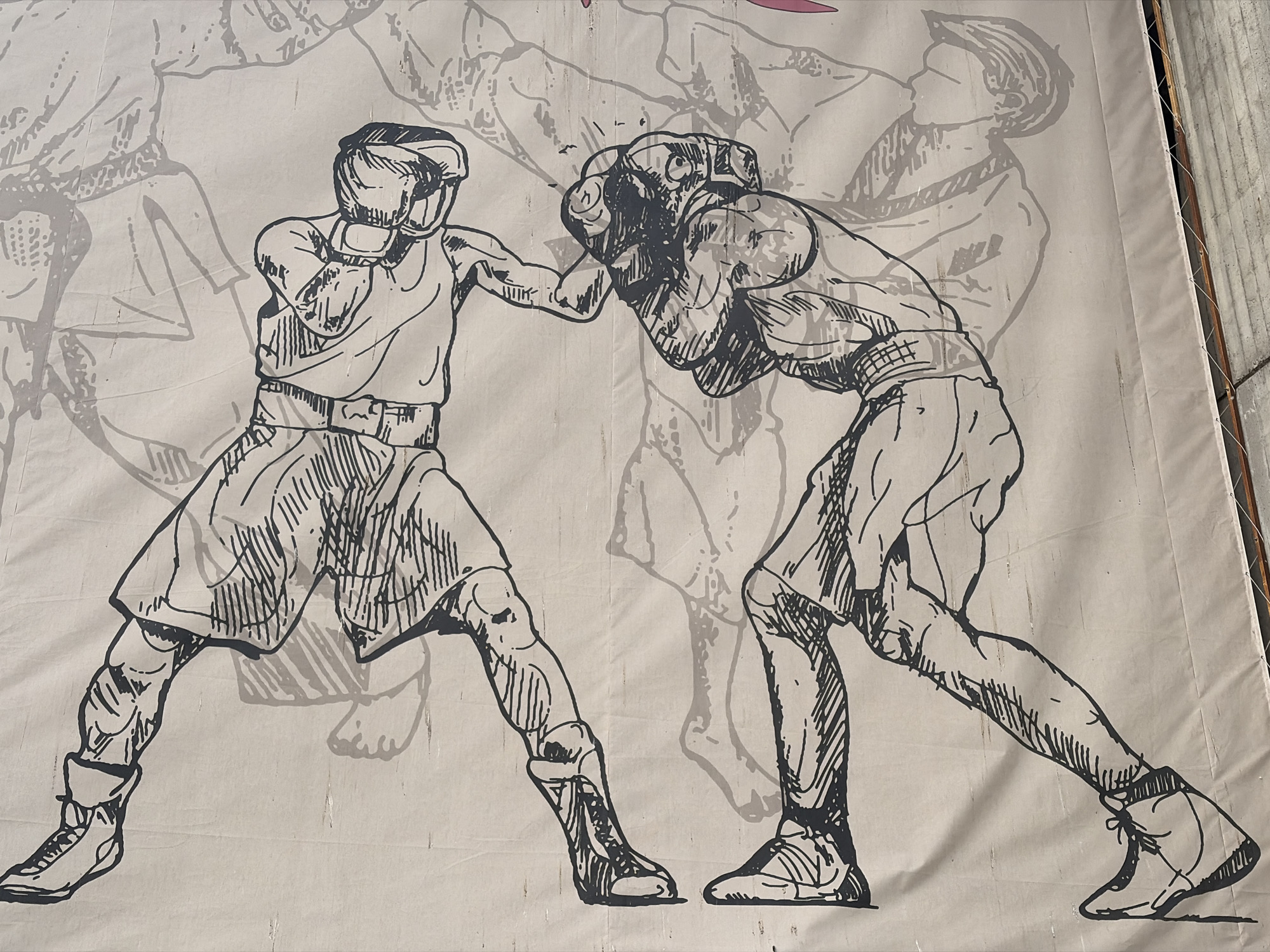 The image shows a large poster of two boxers in a sketched style, with one boxer throwing a punch and the other defending. The poster is a black and white drawing with gray shadowing. The details show the boxers in boxing gear. The location is Sofia, Bulgaria.