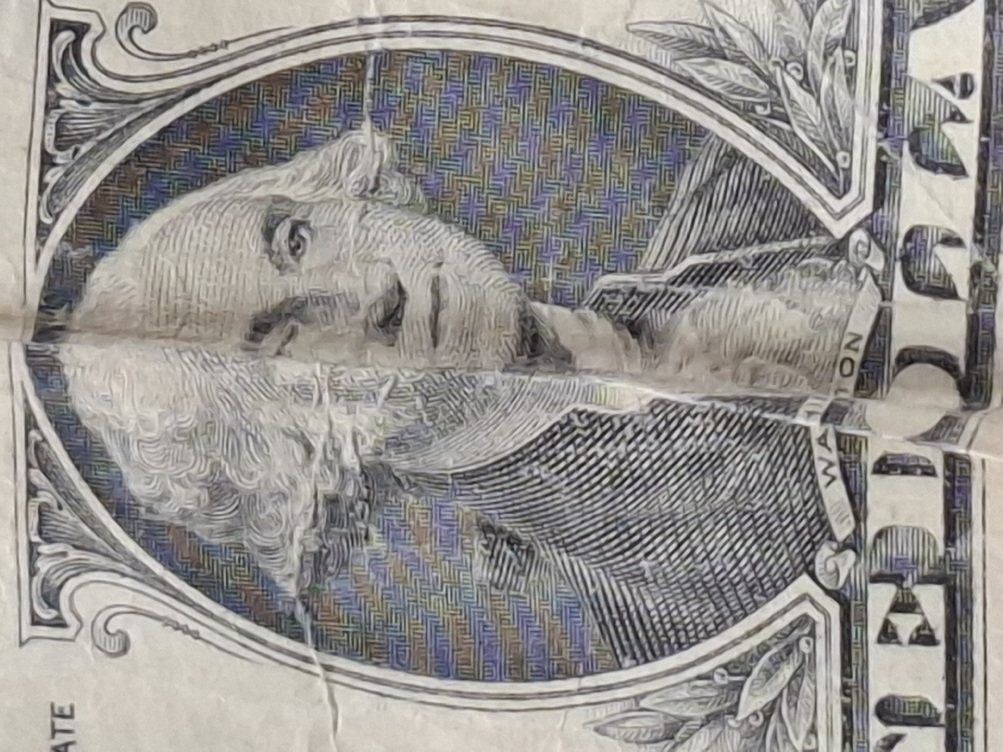 The image shows a close-up, angled shot of a U.S. one-dollar bill. The bill is creased and shows signs of wear. The portrait of George Washington is visible, centered within an oval frame. The background of the portrait is a geometric pattern in shades of blue, yellow, and purple. The words "ONE" and "DOLLAR" are partially visible at the bottom of the bill. The location in the city of Almaty, Kazakhstan is not determinable from the image.
