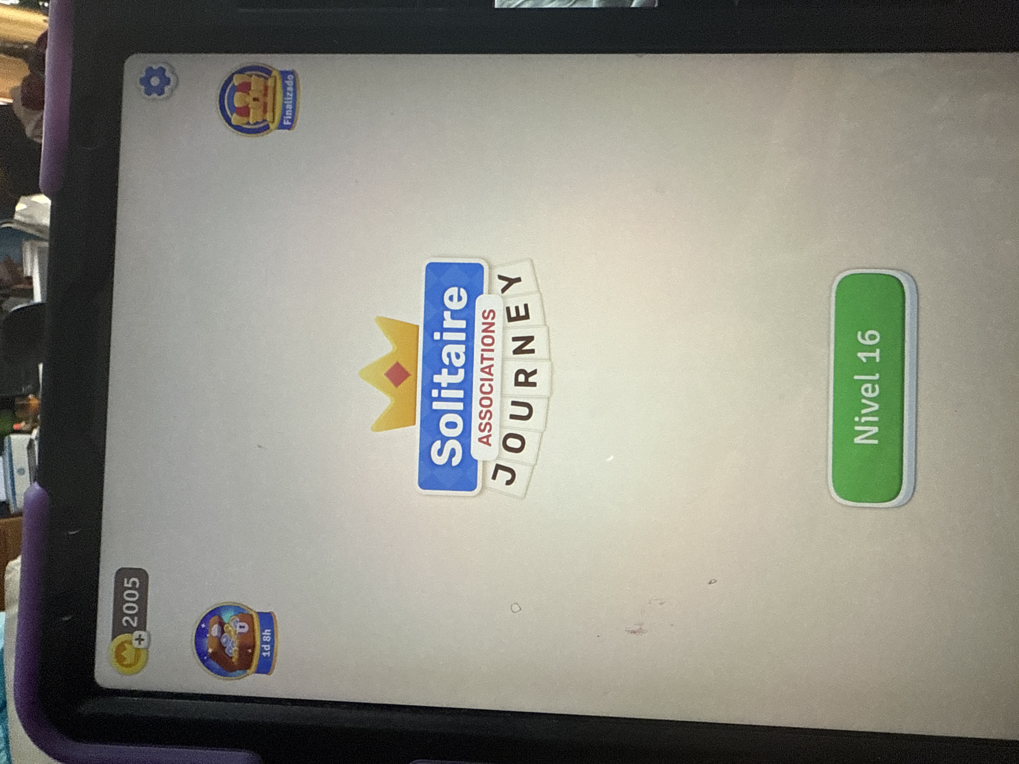 The image shows a tablet screen displaying the title screen of the mobile game "Solitaire Associations Journey." The user has 2005 coins and is about to start level 16. The tablet is surrounded by a purple case and appears to be lying on a soft surface, possibly fabric. The background behind the tablet is out of focus but seems to contain some furniture and household items. There is no indication of the location being Xochitepec, Mexico.