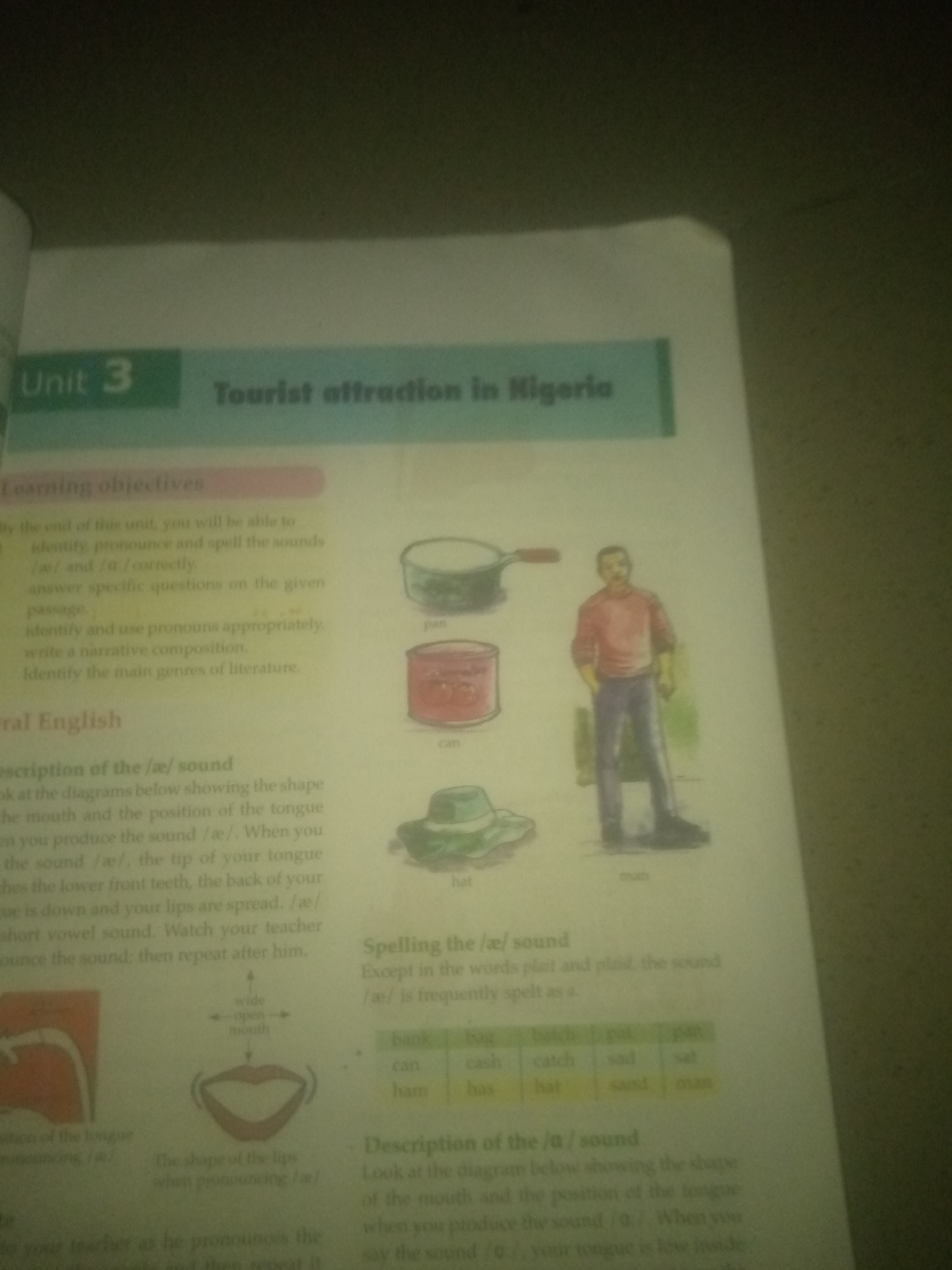 This image shows a page from a textbook. The title of the unit is "Tourist attraction in Nigeria". The page contains text and illustrations related to language learning, specifically pronunciation of vowel sounds and descriptions of some tourist attractions. There are diagrams of a mouth showing the shape for pronouncing vowel sounds, and illustrations of a frying pan, a jar, a hat, and a man. A table of words is also present, likely for practicing pronunciation. The text mentions "Jauro Yinu" in the context of describing a tourist attraction, implying it is a location in Nigeria.