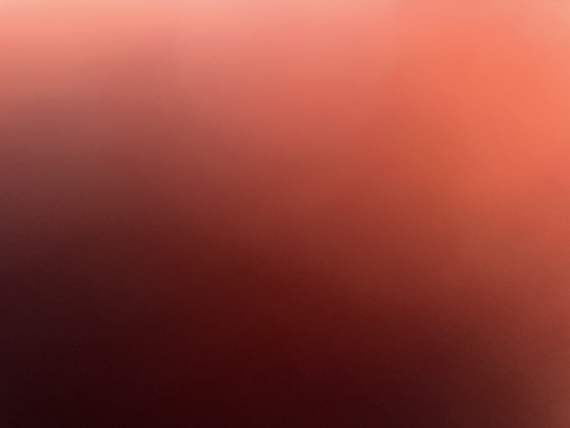 The image is an abstract photograph with a gradient of colors ranging from dark red to light pink. There are no discernible subjects such as people, objects, or specific scenes. The lighting appears to be soft, possibly from a diffused light source, creating a gentle transition between the colors. The overall impression is one of warmth and subtlety. The image lacks any specific details that would indicate the time of day, weather conditions, or a particular location. There is no visible text in the image. The abstract nature of the photograph makes it impossible to determine any activity or event taking place.