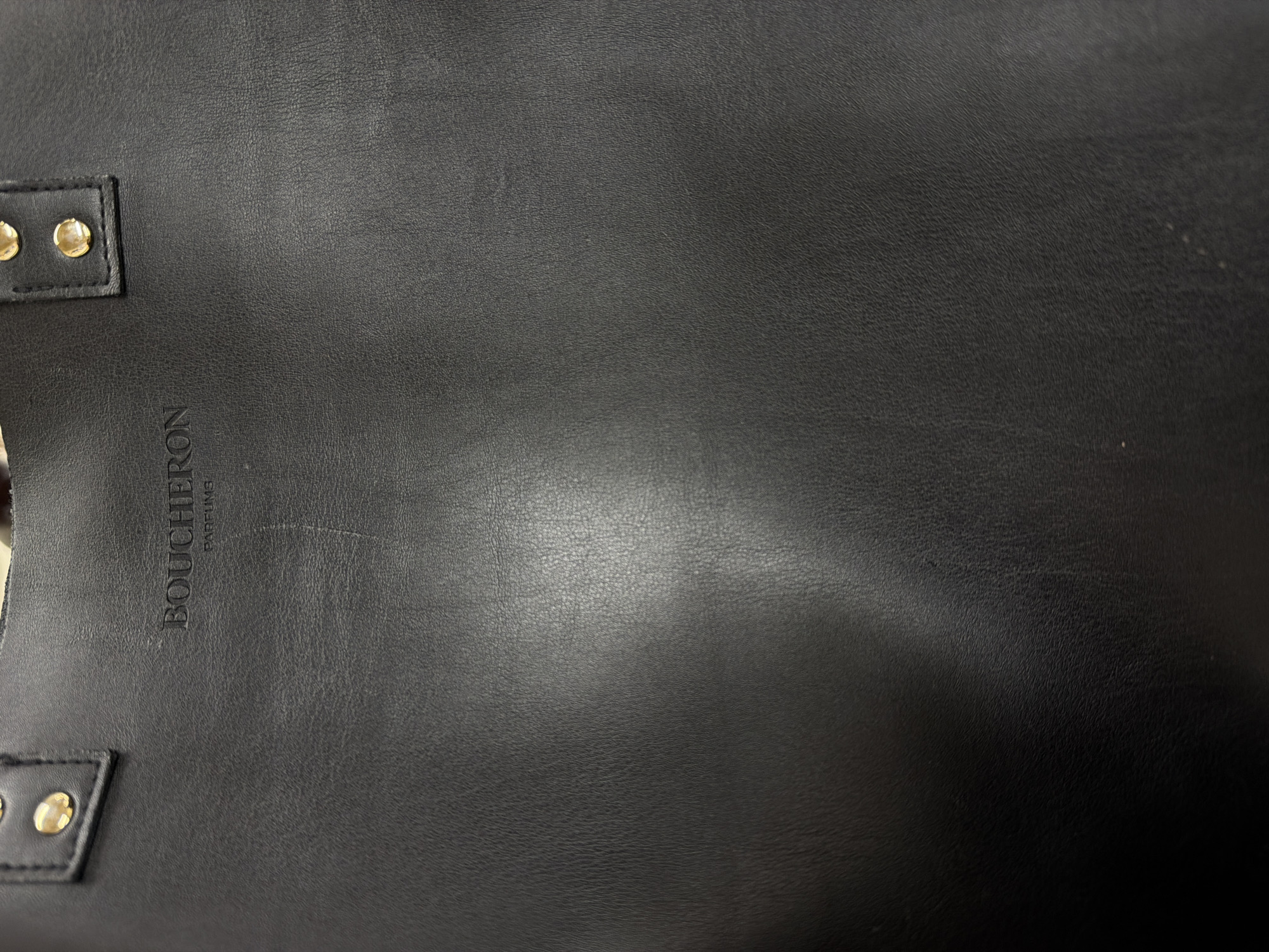 The image shows a close-up of a black leather bag with gold-colored studs on the straps. The brand name "BOUCHERON PARFUMS" is vertically embossed on the leather. The image does not provide information about the city of Sofia, Bulgaria.