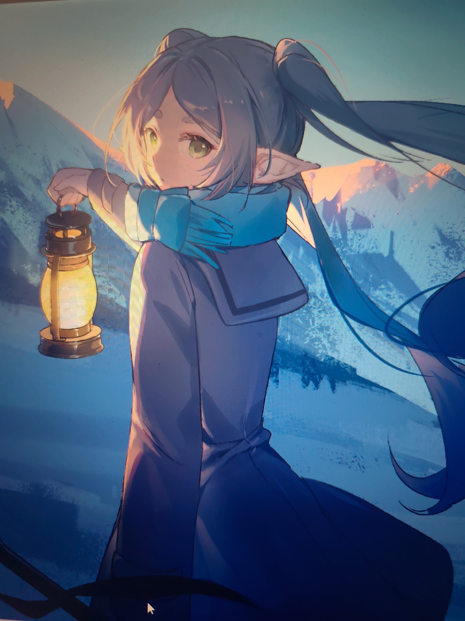 The location is in the city of Unknown, Unknown.
A digitally rendered anime-style illustration, displayed on a screen, features a character in a mountainous, outdoor environment. The central figure, an individual with light purplish-gray hair styled in long twin tails and front bangs, possesses pointed ears and large light green eyes. They are depicted looking to the left, wearing a blue neck scarf and a dark blue, long-sleeved coat. The character holds a lit, brass-toned lantern in their left hand, which emits a bright yellow-orange light, casting warm illumination on their face, hands, and the immediate area of their clothing. The background comprises a range of mountains, with their upper slopes and peaks highlighted by a soft orange-pink light, possibly from a sunrise or sunset, against a cool blue-to-teal gradient sky. The lower environment transitions to deeper shades of blue, suggesting deep shadows or a cold, desolate landscape. A mouse cursor is visible in the lower right corner of the display.