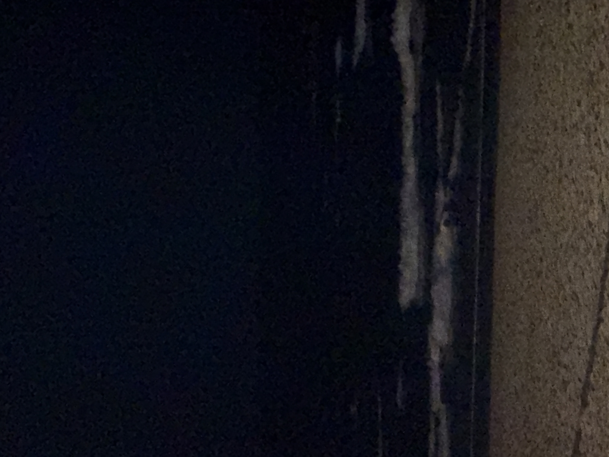 The image shows a close-up of a dark, possibly navy blue, flat surface on the left side of the frame. To the right of this surface is a narrower vertical strip with lighter, greyish markings. The rightmost part of the image is a textured, beige-colored wall or surface.
Without additional information, it's impossible to determine the location in Tel-Aviv, Israel.