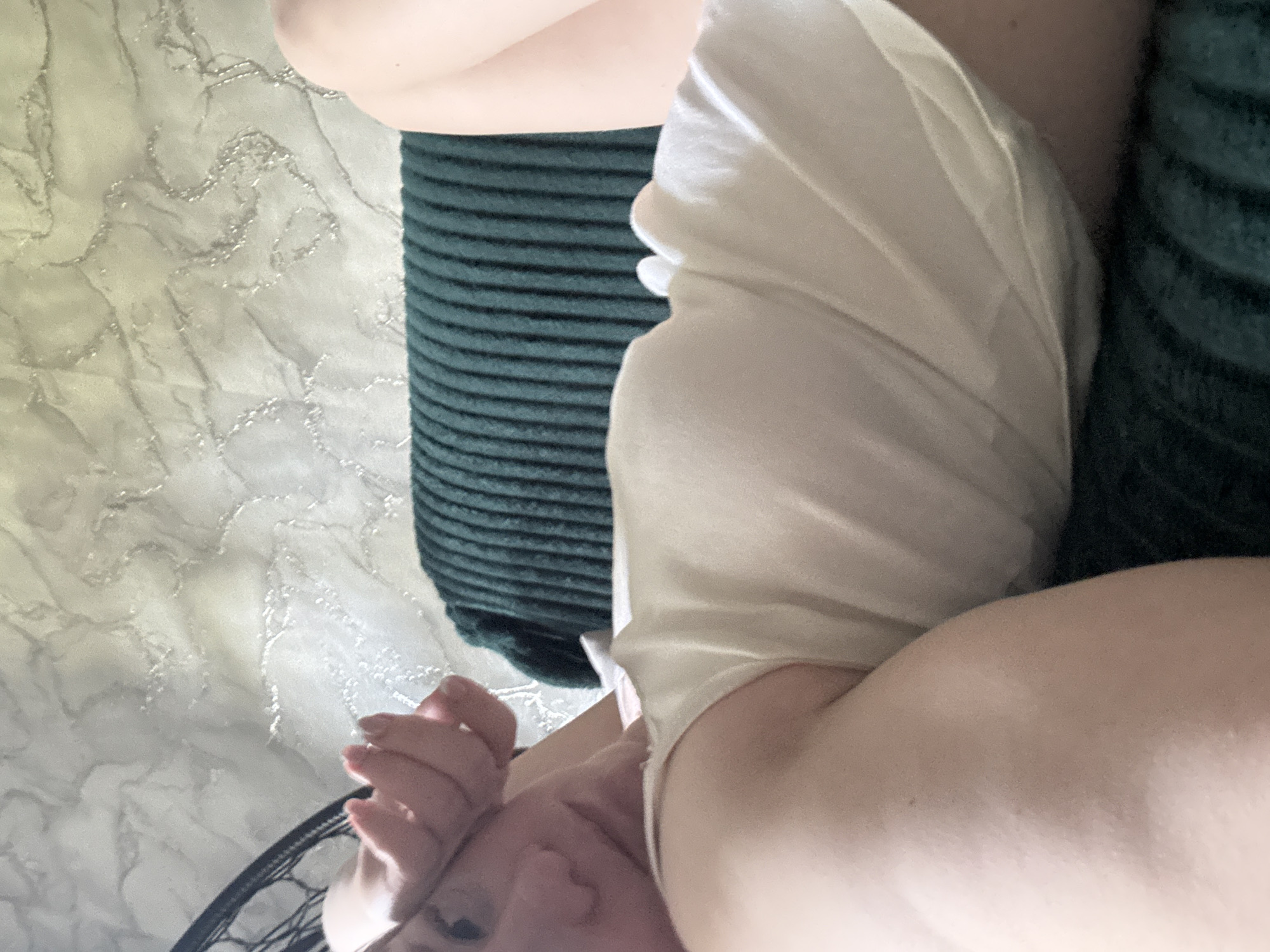 A close-up, tilted shot features a person sitting on what appears to be a corduroy-covered cushion, with a marble-patterned surface visible in the background. The person is wearing a light-colored, draped garment. Part of their face, including an eye and nose, and a hand are visible. The location in Chaikovsky, Russia, cannot be determined from the image.