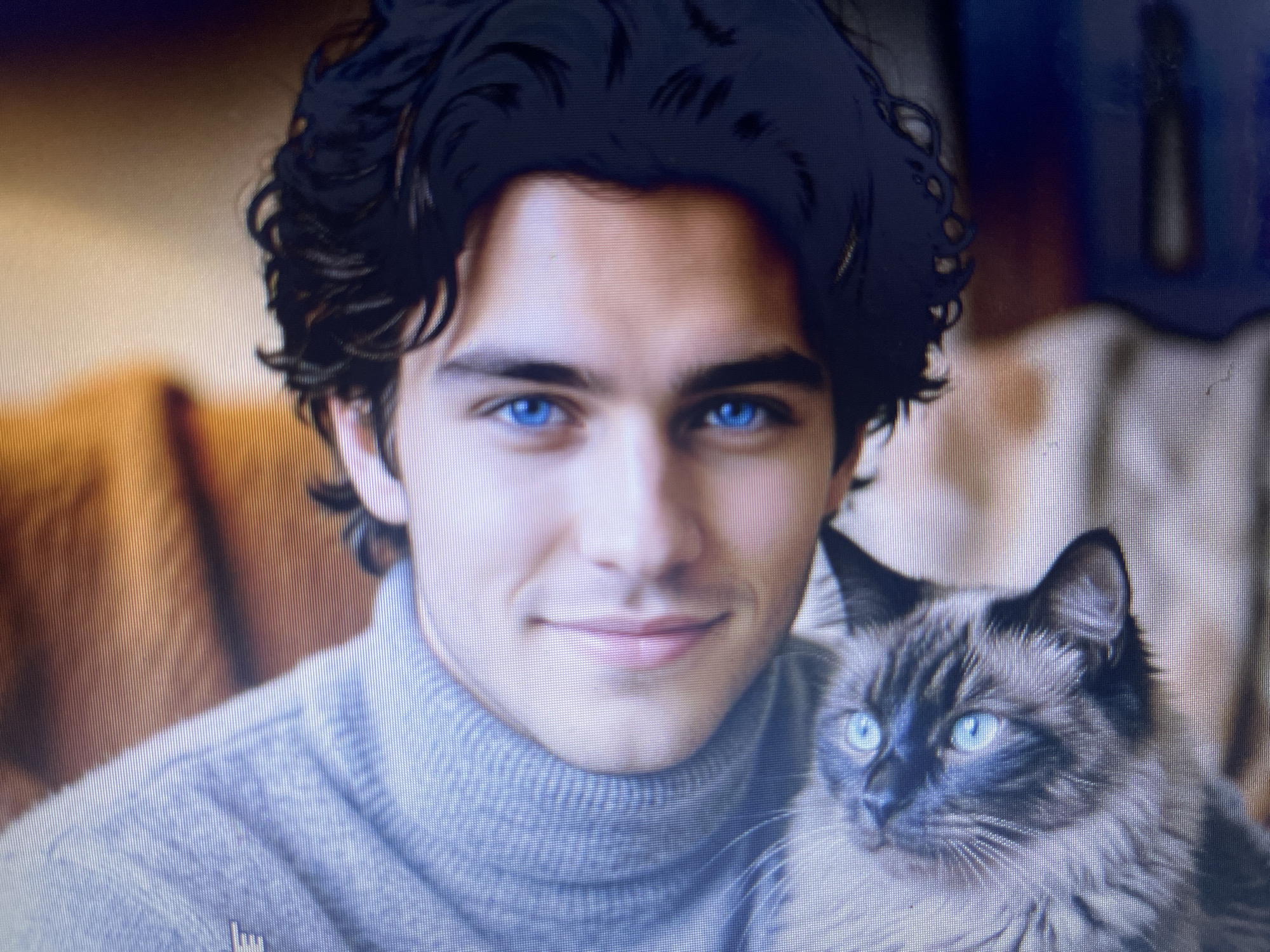The image shows a close-up portrait of a young man with dark, curly hair and striking blue eyes, holding a fluffy cat with similar blue eyes. They are both wearing neutral-colored clothing. The background is out of focus, suggesting an indoor setting, possibly a home. There is no identifiable information within the image to suggest a specific location in Stary Oskol, Russia.