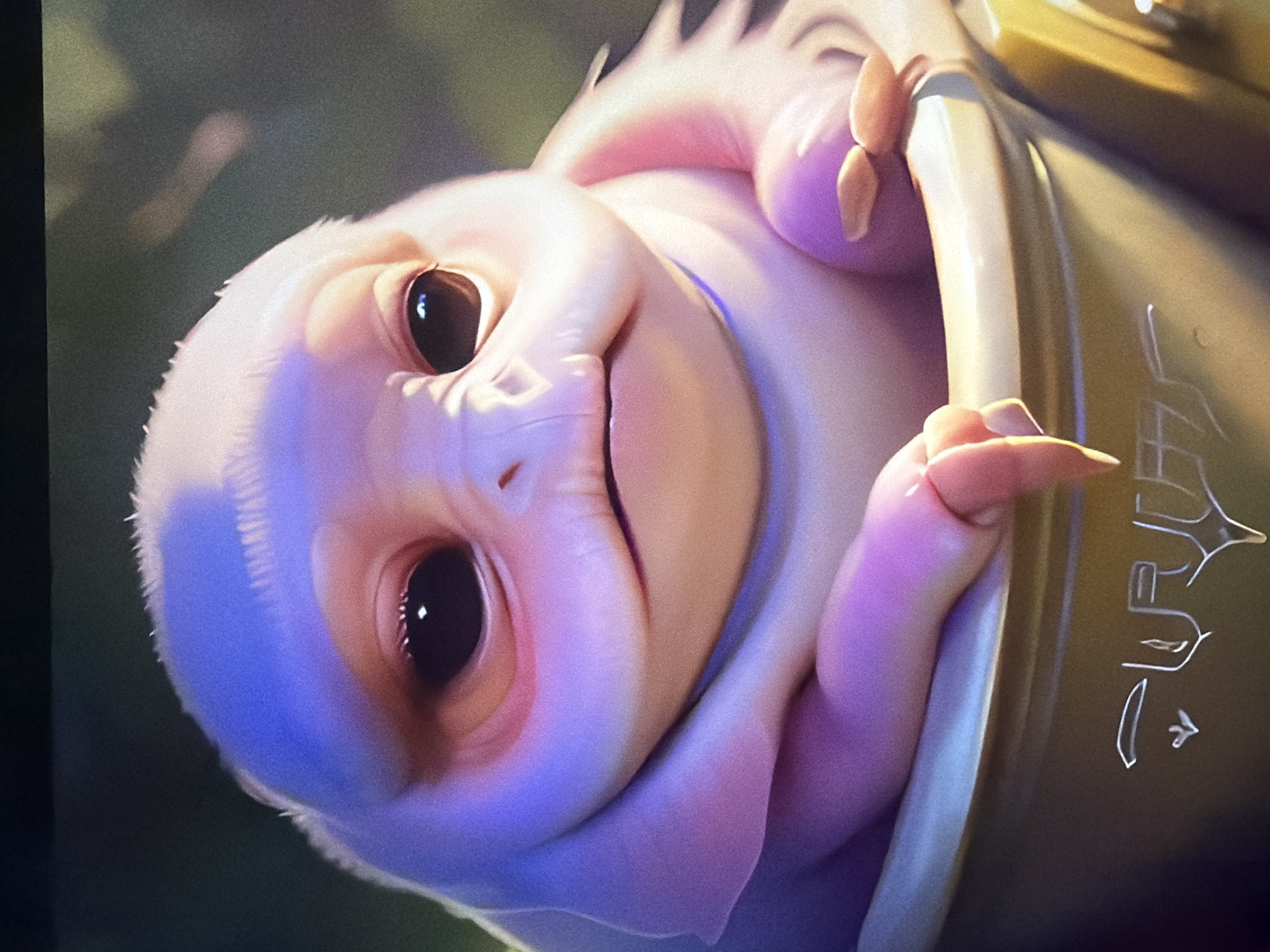 The image shows a close-up, slightly blurry, digitally rendered depiction of a small, pale creature with large, dark eyes and a soft, rounded body. The creature is pink and light purple, with subtle highlights and shadows that give it a three-dimensional appearance. It is positioned in what appears to be a shallow, golden-colored container or bowl, which has some sort of engraved symbols on its surface. The background is out of focus, suggesting a natural environment with hints of green foliage. There is no information in the image that indicates a specific location in Kyiv, Ukraine.