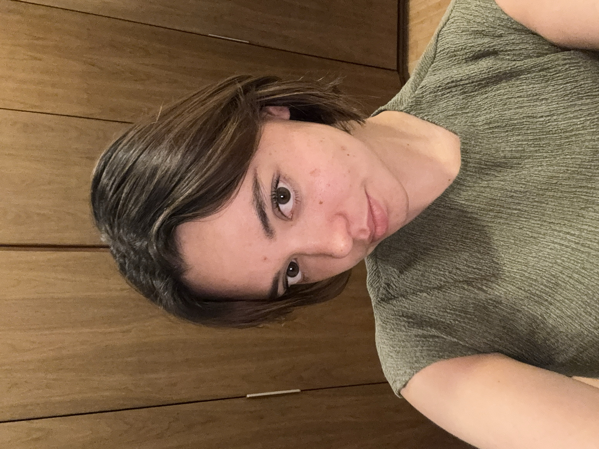 A medium shot depicts a person with fair skin and short, dark brown hair. The person is wearing a green textured shirt. The background consists of wooden paneling. There is no indication of this being in San Bernardino Tlaxcalancingo, Mexico.