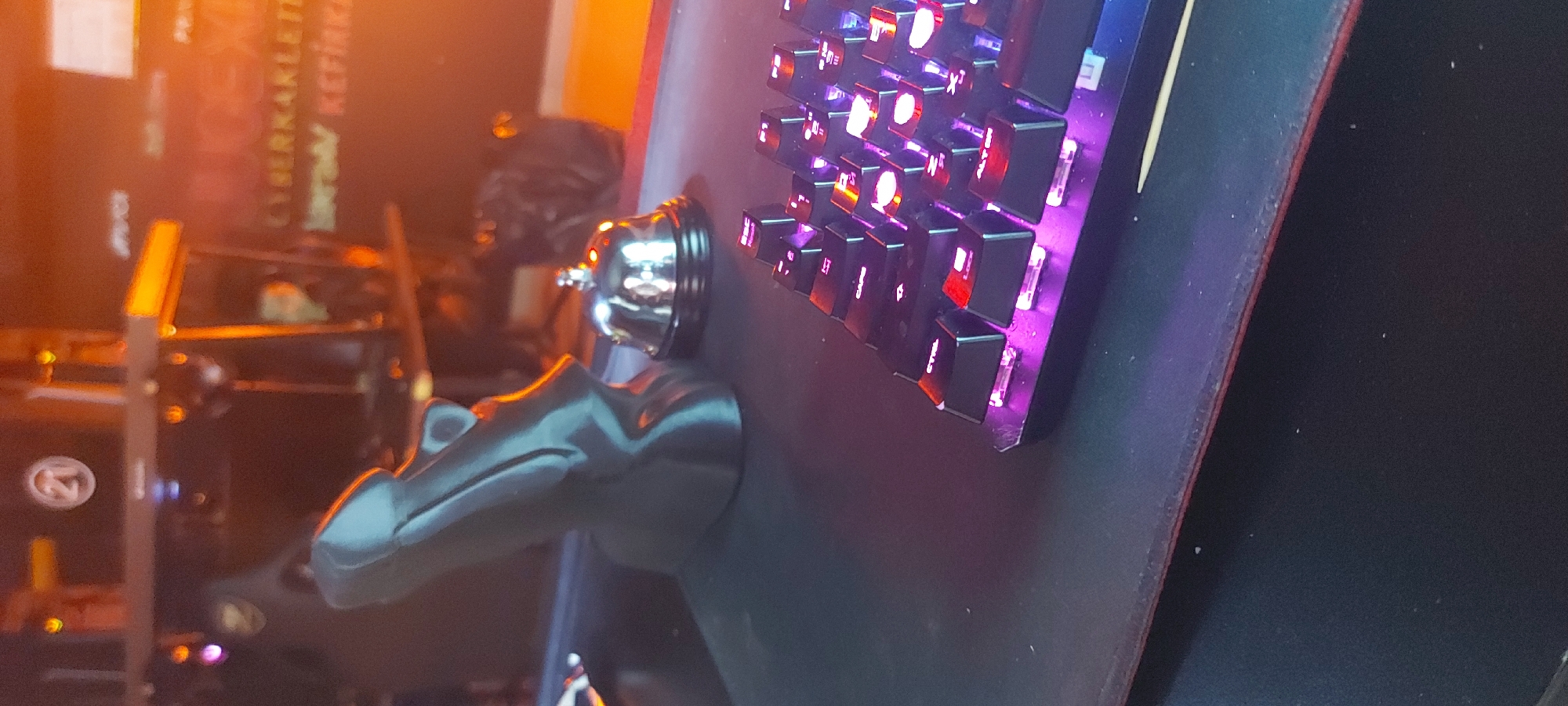 The image shows a silver service bell mounted on a dark-colored base with an adjacent keyboard with lit keys. The background is blurry, with glimpses of a book labeled "CYBERKAKLEITTI" and some other objects. It is difficult to give exact details or location in Tashkent, Uzbekistan.