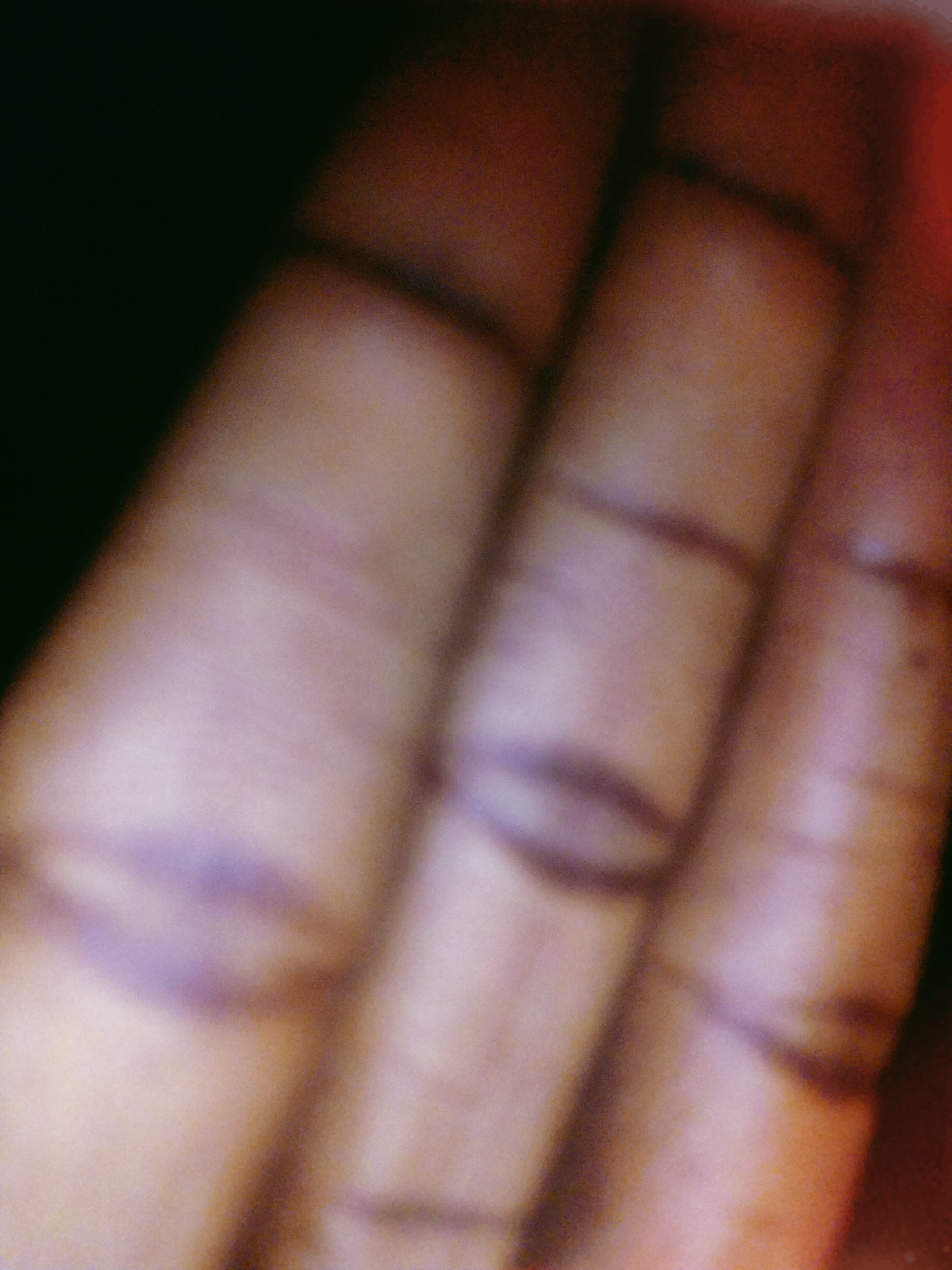 The image shows a blurred close-up of the fingers of a hand. The skin tone appears to be brown. There are visible creases at the joints of the fingers. Due to the blur, specific details about the hand's texture or any markings are indistinct. The background is mostly dark and out of focus. There is no contextual information that could link the image to a specific location in Uyo, Nigeria, or indicate any actions, interactions, or specific subjects.