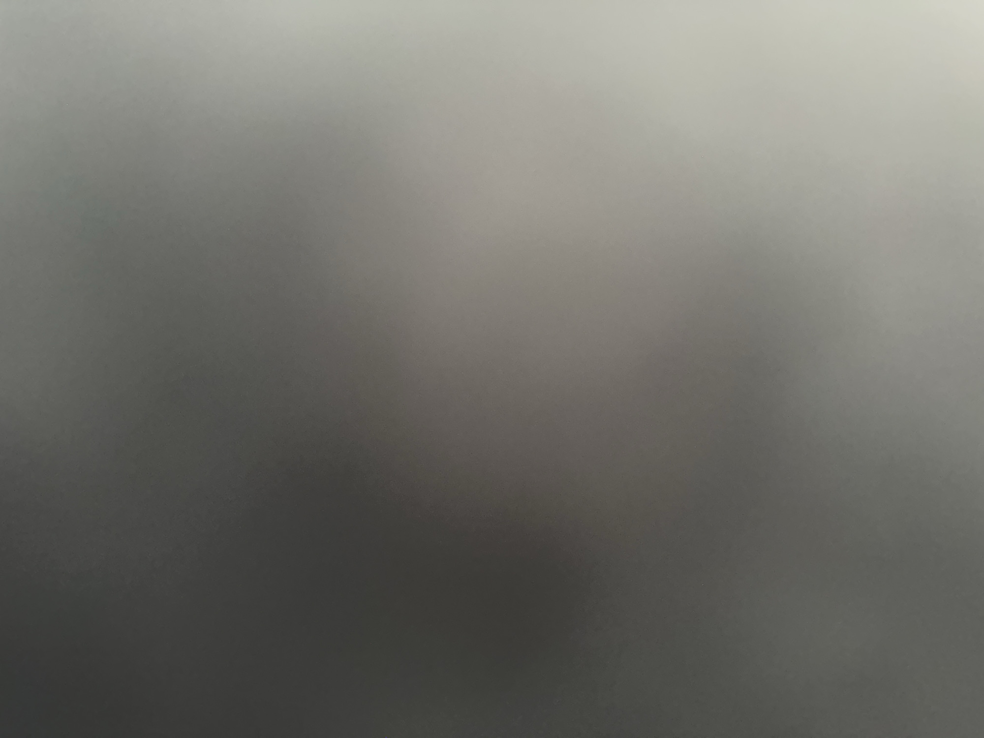 The image is an abstract, out-of-focus photograph, appearing to be a gradient of grays and whites. There are no discernible subjects, objects, scenes, or activities. The lack of detail prevents any interpretation of time of day, weather, location cues, or emotions. No text is visible. The image's abstract nature suggests it may be a result of intentional artistic choice or an accidental capture.
