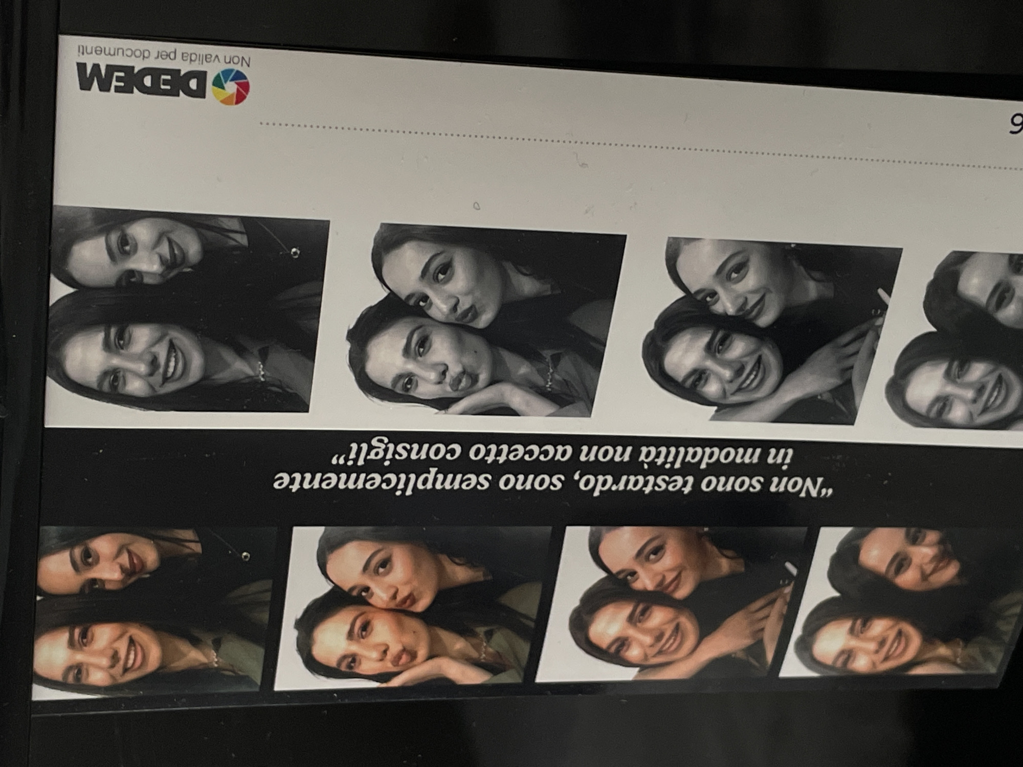 The image shows a strip of photo booth pictures of two women together. They are in various poses in the photos. Text above the photos reads "Non sono testardo, sono semplicemente in modalità non accetto consigli" and "DEDEM Non valida per documenti." There is also the number "6" at the top right. The text is in Italian. The photo strip appears to be resting on a dark surface. Based on the company name "DEDEM", and the text language, the image is likely from Italy. Given that DEDEM has branches in Milan, I can speculate that the image is in Milan, Italy.