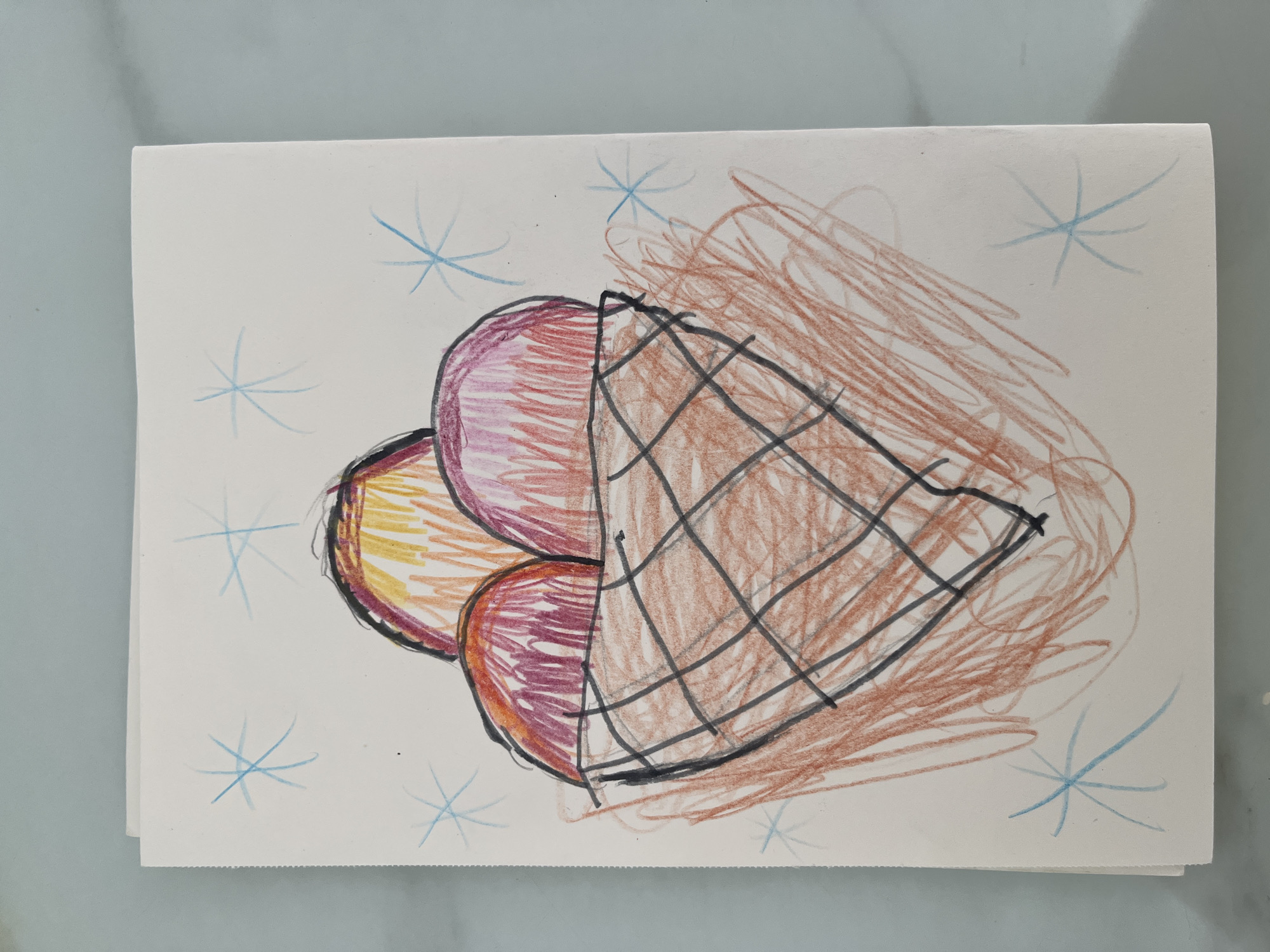 A child's crayon drawing depicts a triple-scoop ice cream cone. The ice cream scoops are colored with various shades of red, orange, and purple. The cone is brown with black grid lines. Light blue starbursts are drawn on the white background surrounding the ice cream. The location is not discernible in the image.