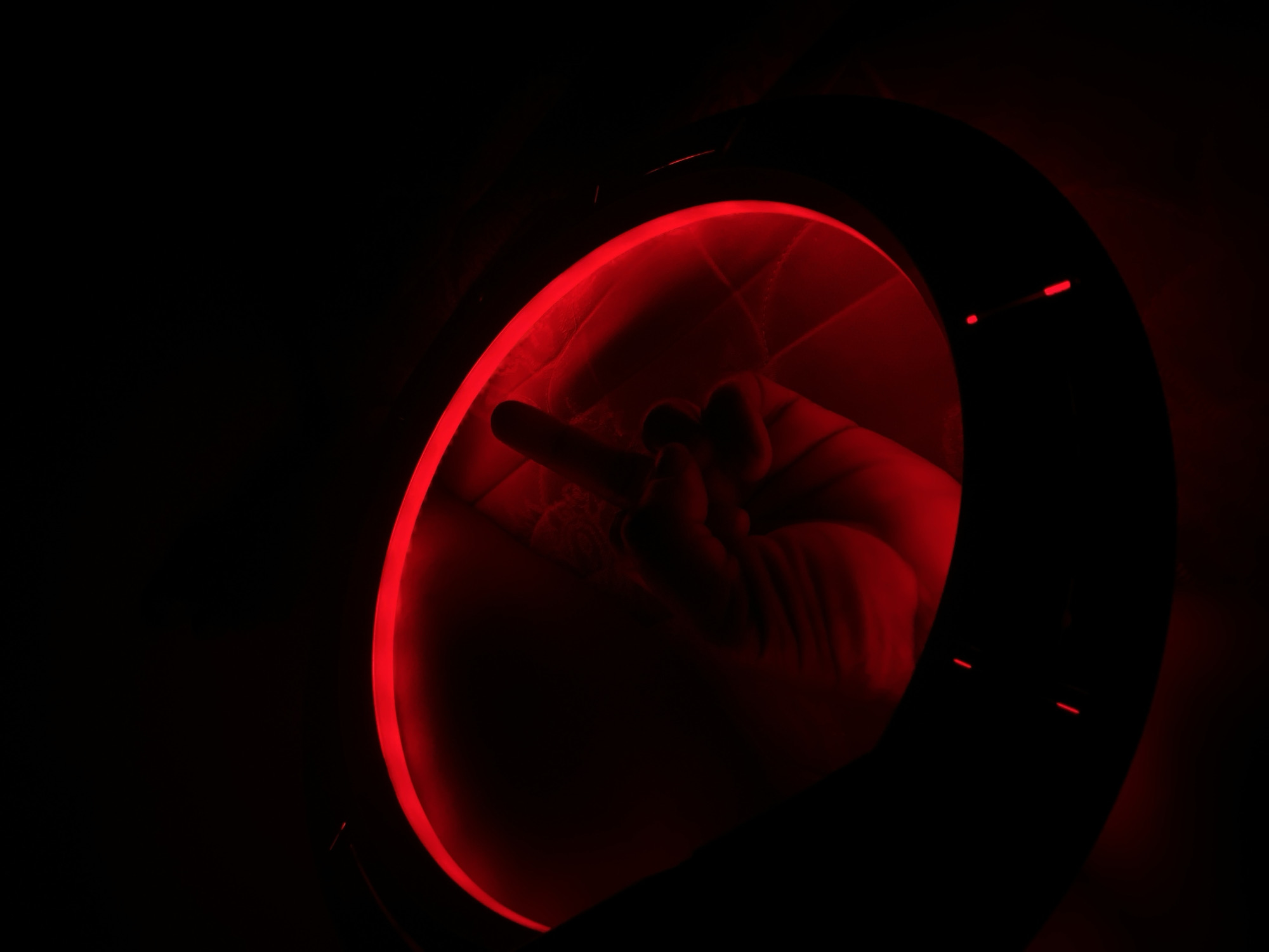 A hand is shown making an obscene gesture within a circular red-lit opening in a dark environment. The scene is not identifiable as being in Maigizo, Nigeria.