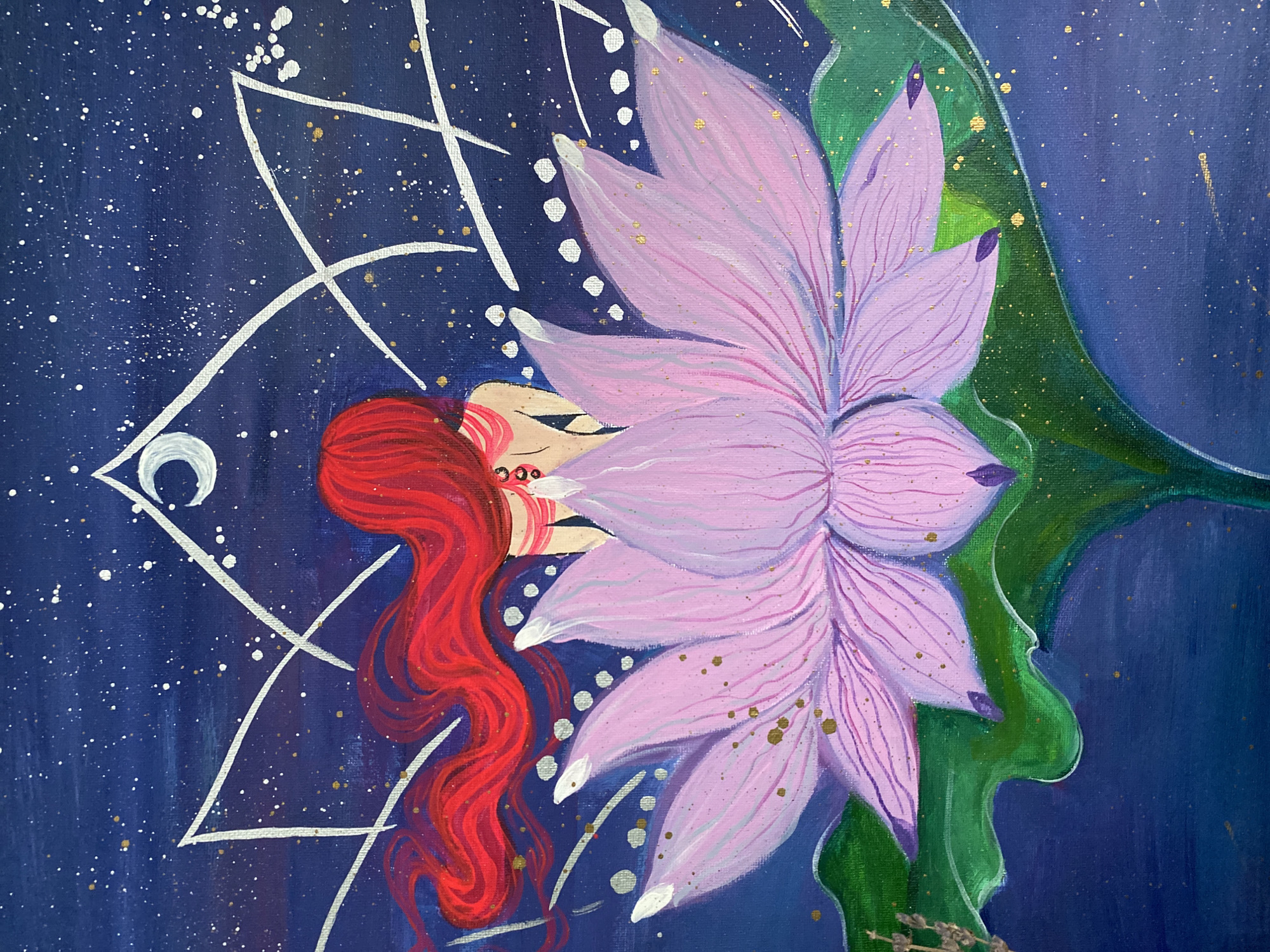 The image is a close-up of an art painting. The background is a dark blue speckled with white and gold, creating a starry night effect. Superimposed on this is a white geometric pattern. A woman with long, flowing red hair lies sideways with her eyes closed. She is partially obscured by a large pink lotus flower with white tips on some petals. Green leaves are partially visible behind the flower. The painting style appears to be acrylic on canvas. The location of Chaikovsky, Russia, is not evident from the image.