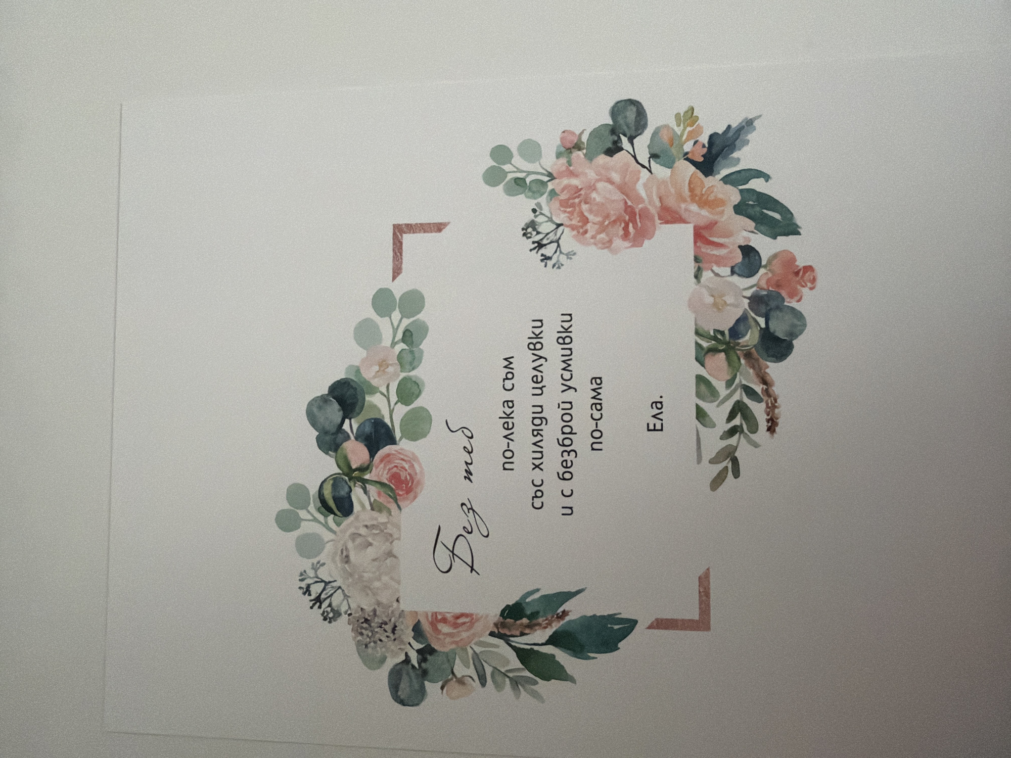 The image displays a postcard or a piece of stationery with a floral border. The text within the floral arrangement is in Bulgarian. The top line of text, "Без теб" (Bez teb), is written in a script font and translates to "Without you". Below this, in a standard font, are the lines: "по-лека съм" (po-leka sam) - "I am lighter", "със хиляди целувки" (sas hilyadi tseluvki) - "with thousands of kisses", "и с безброй усмивки" (i s bezbroy usmivki) - "and with countless smiles", and "по-сама" (po-sama) - "alone" or "by myself". The final line of text is "Ела." (Ela.) which means "Come.". The floral design consists of watercolor illustrations of roses, eucalyptus leaves, and other delicate flowers in shades of pink, peach, white, and green. The background is plain white. There is no information within the image that indicates a specific location in Pazardzhik, Bulgaria.