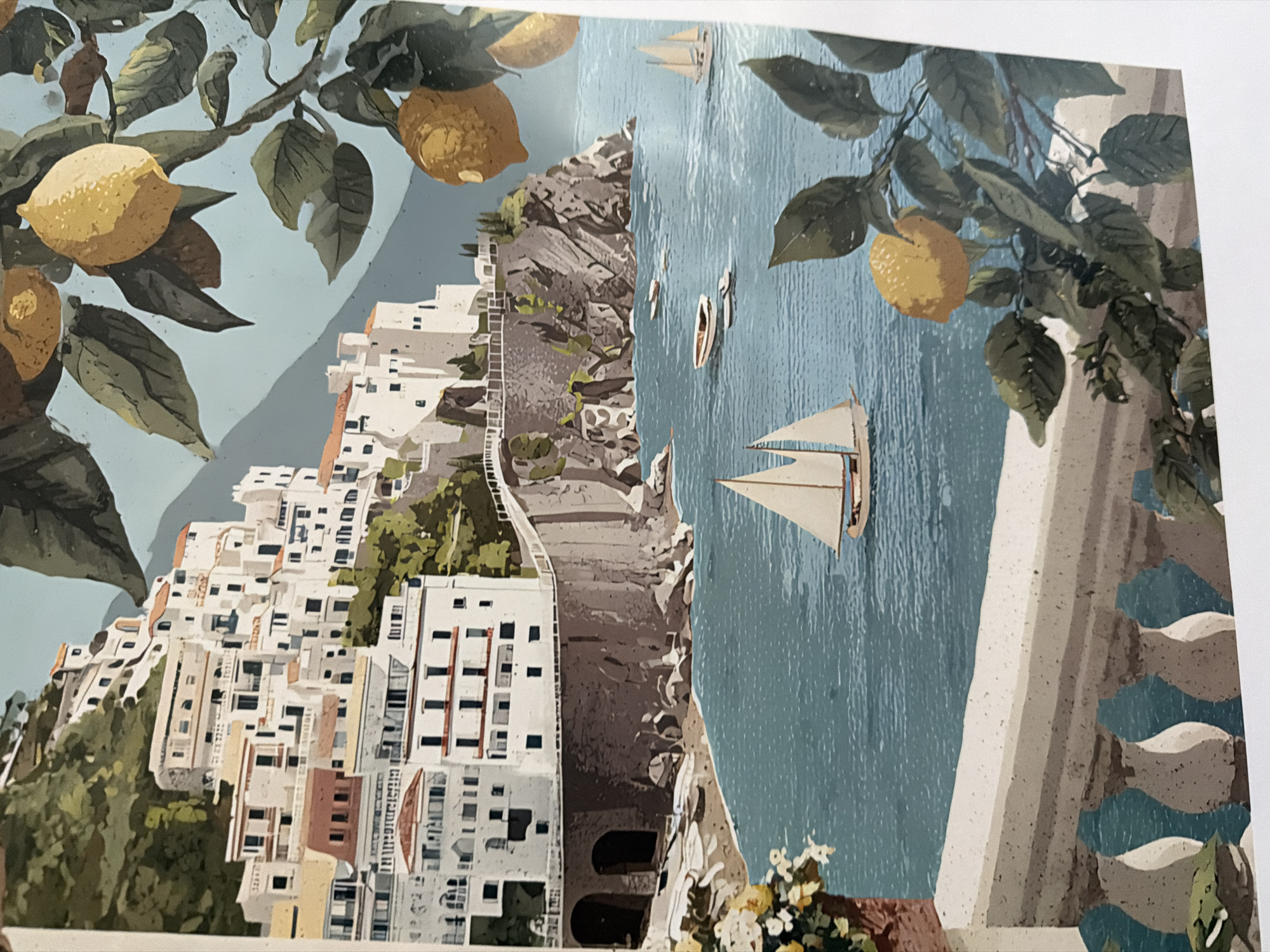This is an illustration of a coastal town with buildings cascading down a hillside towards the sea. The architecture is predominantly white with red-tiled roofs. The sea is a vibrant blue and dotted with small boats, including a white sailboat in the foreground. There is a cliff face with rocky outcrops and some greenery. In the foreground, a balustrade overlooks the scene, and a branch with lemons and leaves hangs into the frame. The background features a light blue sky. There are no people or identifiable landmarks suggesting the city of Sofia, Bulgaria.