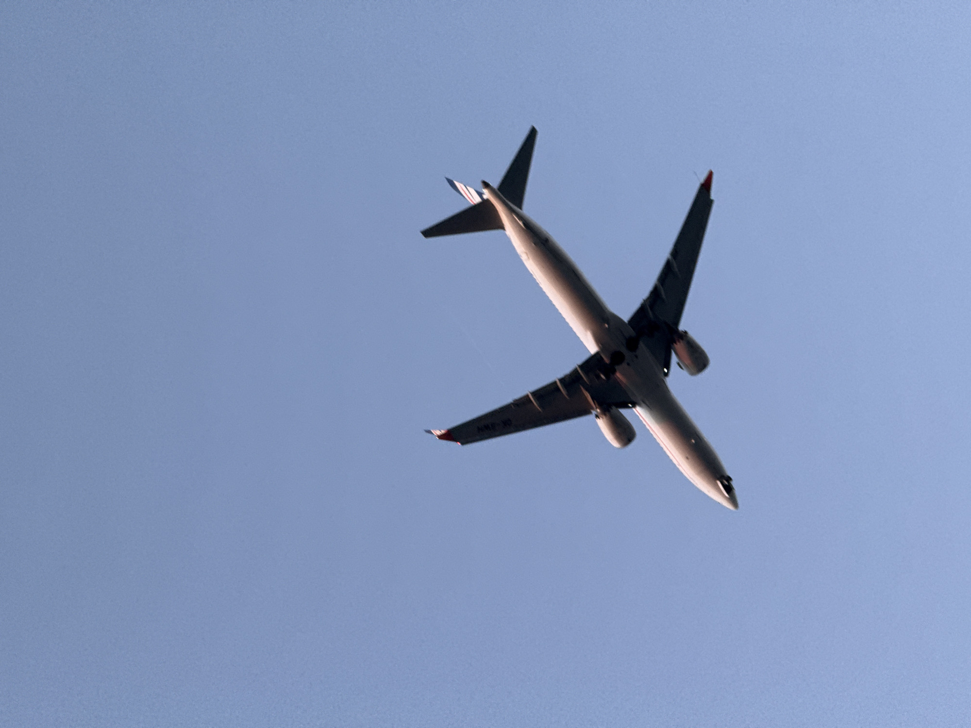 This media file shows a commercial airplane in flight against a clear blue sky. The airplane is seen from below, with its wings and fuselage angled towards the viewer. The sunlight illuminates the underside of the aircraft, highlighting its sleek design. The plane appears to be a wide-body jet, likely engaged in passenger transport or cargo operations.
The setting is an open sky, suggesting the plane is at a considerable altitude. The weather appears to be clear and fair, with no clouds visible. The time of day is likely daytime, given the bright illumination on the aircraft. There are no discernible location cues in the sky itself.
The activity taking place is simply air travel. The plane is in motion, soaring through the atmosphere. No people are visible, and the focus is solely on the aircraft.
A notable detail is the presence of some text on the wing of the airplane, which appears to be registration markings. While not entirely clear due to the resolution and angle, it is possible to make out some characters, such as "A6-..." followed by other digits. This indicates the aircraft's registration, likely for identification purposes by aviation authorities.
The image evokes a sense of freedom and vastness, with the airplane a symbol of modern travel connecting distant locations. The clear sky and bright light contribute to a feeling of openness and possibility. The specific location context of Burgas, Bulgaria, might imply the plane is either departing from, arriving at, or flying over the region, contributing to air traffic in that area.