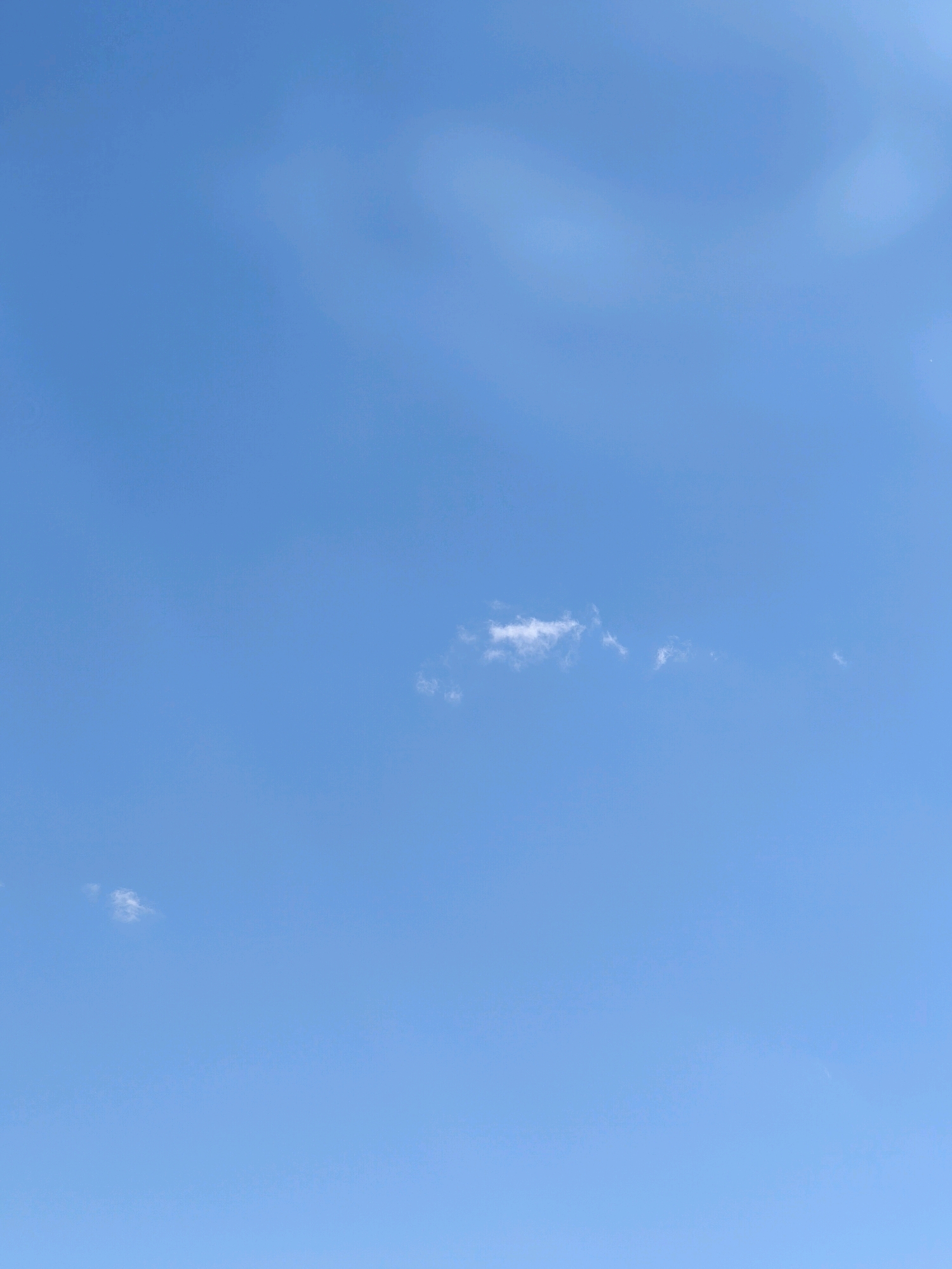 The image depicts a clear blue sky with a few scattered, wispy white clouds. The sky is a vibrant azure, suggesting good weather. There are no discernible objects or individuals in the frame. The scene appears to be an outdoor environment, possibly taken on a bright day. The image does not provide any specific contextual information about the city of Karachayevsk, Russia, other than it is the stated location.