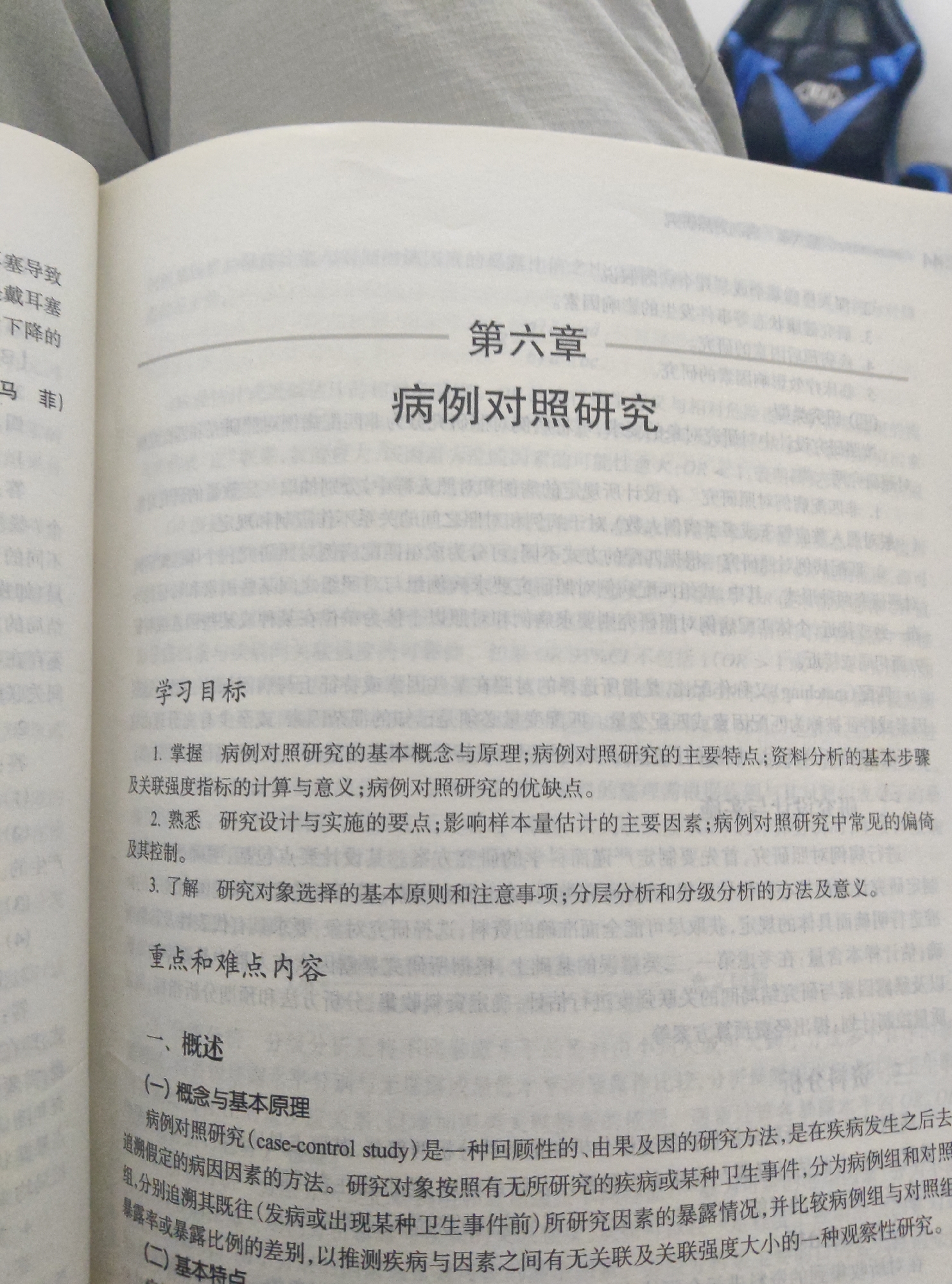 The image is a close-up of an open book, showing pages with Chinese text. The text is printed in black on white paper. The left page has a margin with some text, and the right page contains chapter titles and subheadings. The chapter title is "第六章 病例对照研究" which translates to "Chapter Six Case-Control Study". Below this, there are sections titled "学习目标" (Learning Objectives) and "重点和难点内容" (Key and Difficult Content). The content is educational material, likely from a textbook or academic publication. There are no discernible elements of Chongqing High-tech Zone, China, nor any people or specific actions depicted. The focus is entirely on the text within the book.