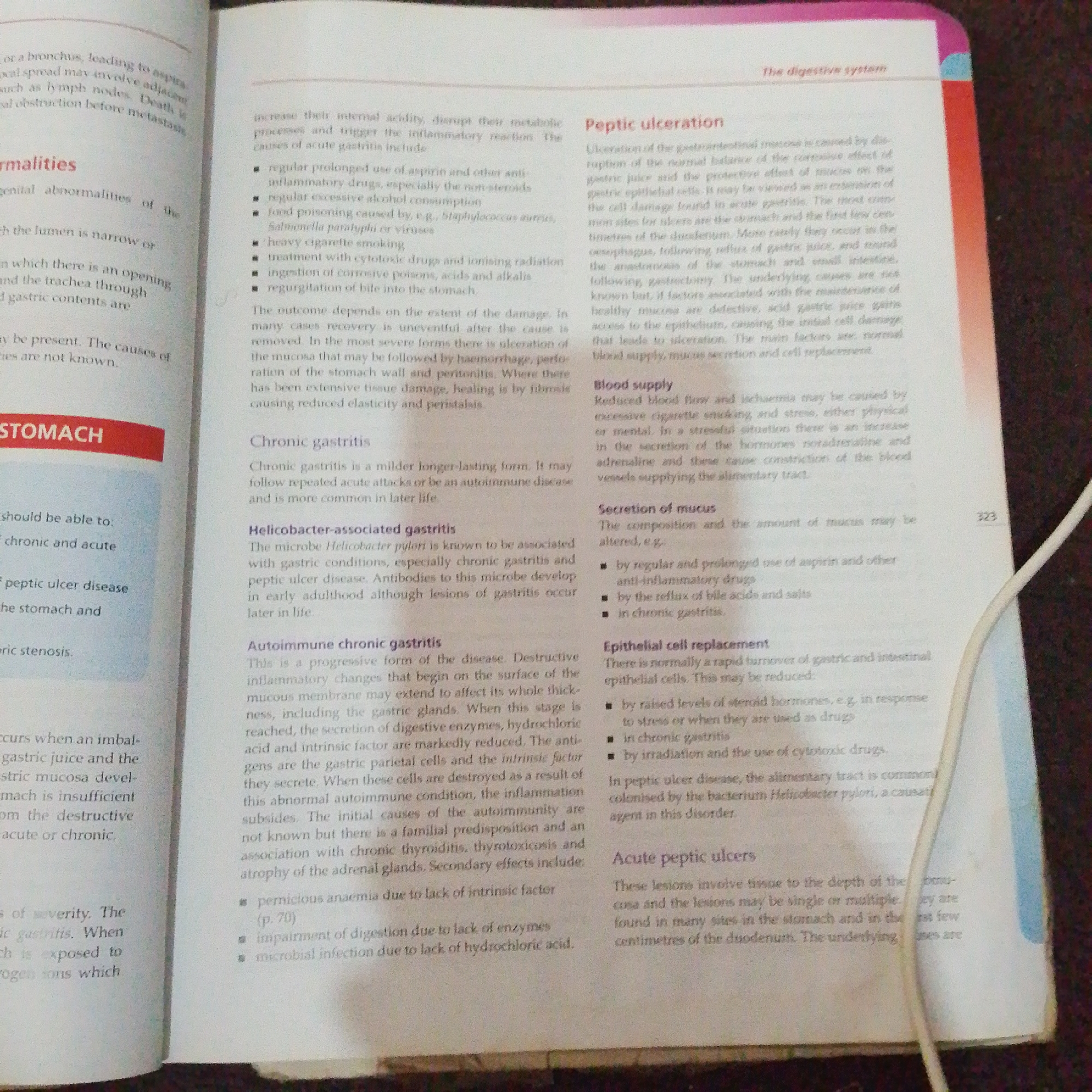 The image displays a page from a medical textbook discussing digestive system issues. The text covers topics such as abnormalities, peptic ulceration, blood supply, secretion of mucus, epithelial cell replacement, and acute peptic ulcers. The page is from the right side of an open book and includes a page number "323" in the upper right corner. The text is printed in black on a white background, with some headings in bold. There is no visible information related to Jalingo, Nigeria, or any specific city. The image captures a portion of the book's content, focusing on medical terminology and explanations.