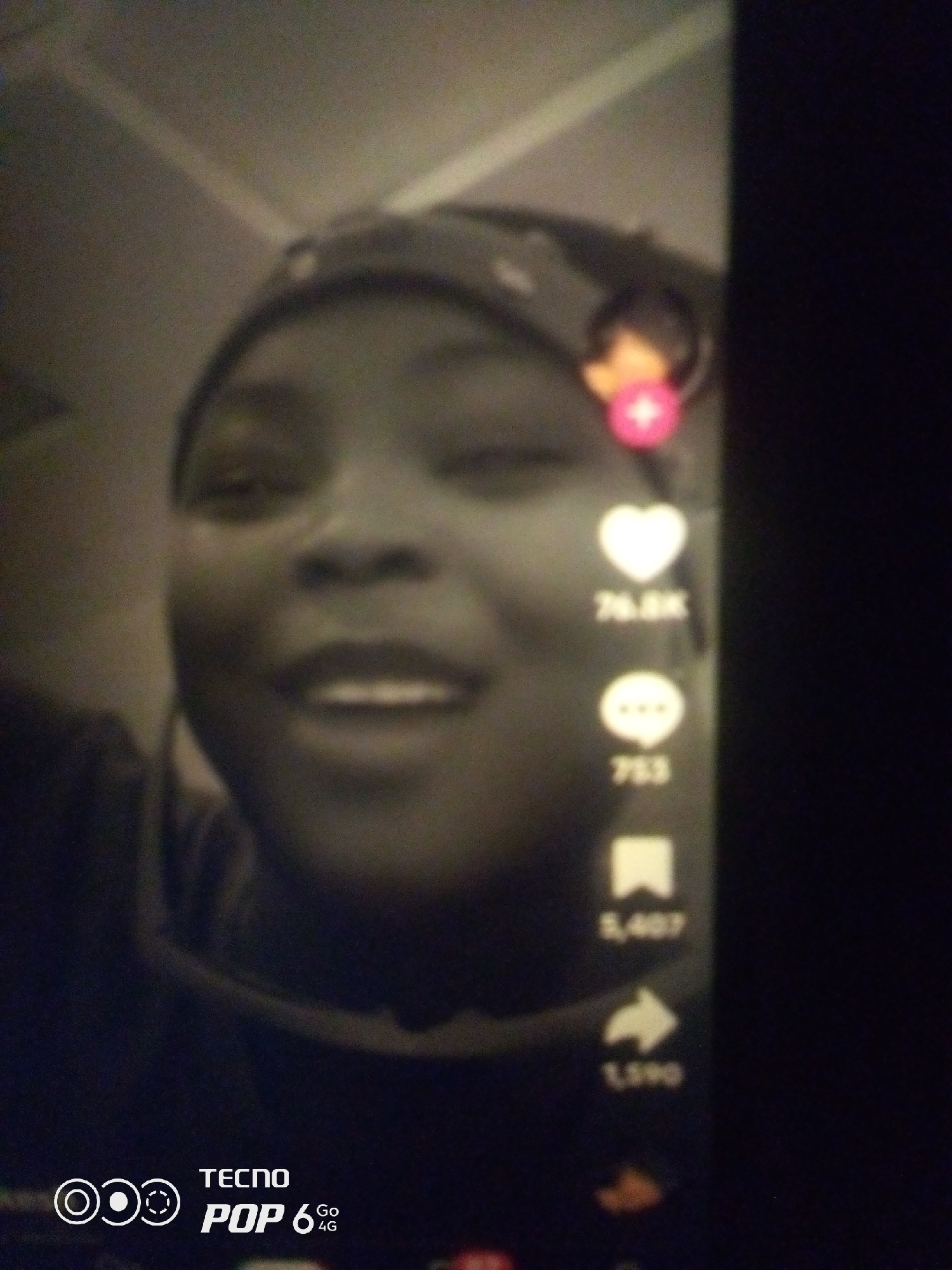 The image shows a person's face with a headscarf, possibly taken from a mobile device. On the right side of the image, there are social media icons, including a heart with the number 76.8K, a speech bubble with 753, a bookmark with 5,407, and a share icon with 1,590. The bottom left corner displays "TECNO POP 6 4G". The background is blurry and appears to be an indoor environment. There is no indication of the city of Howayi, Nigeria, or any specific location information in the image.