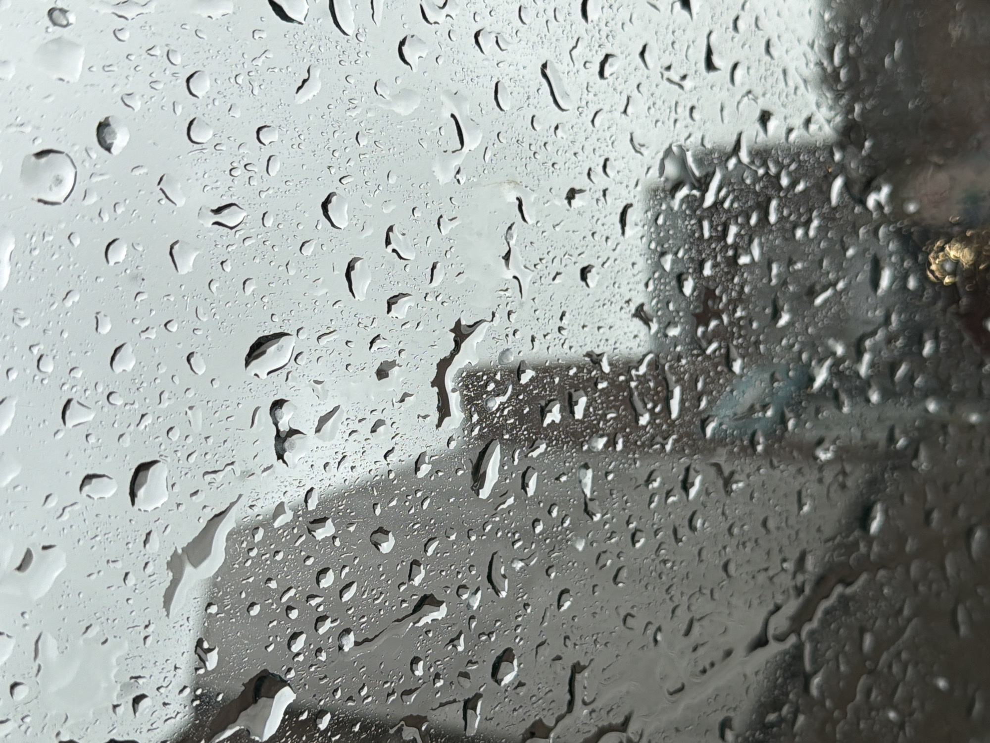 The image shows raindrops on a window, blurring the view outside. The background appears to be an urban scene, with indistinct buildings visible through the rain-streaked glass. The exact location within Durham, United Kingdom is indeterminate from this image alone. There are no people visible, and the focus is on the water droplets and the obscured view beyond the window.