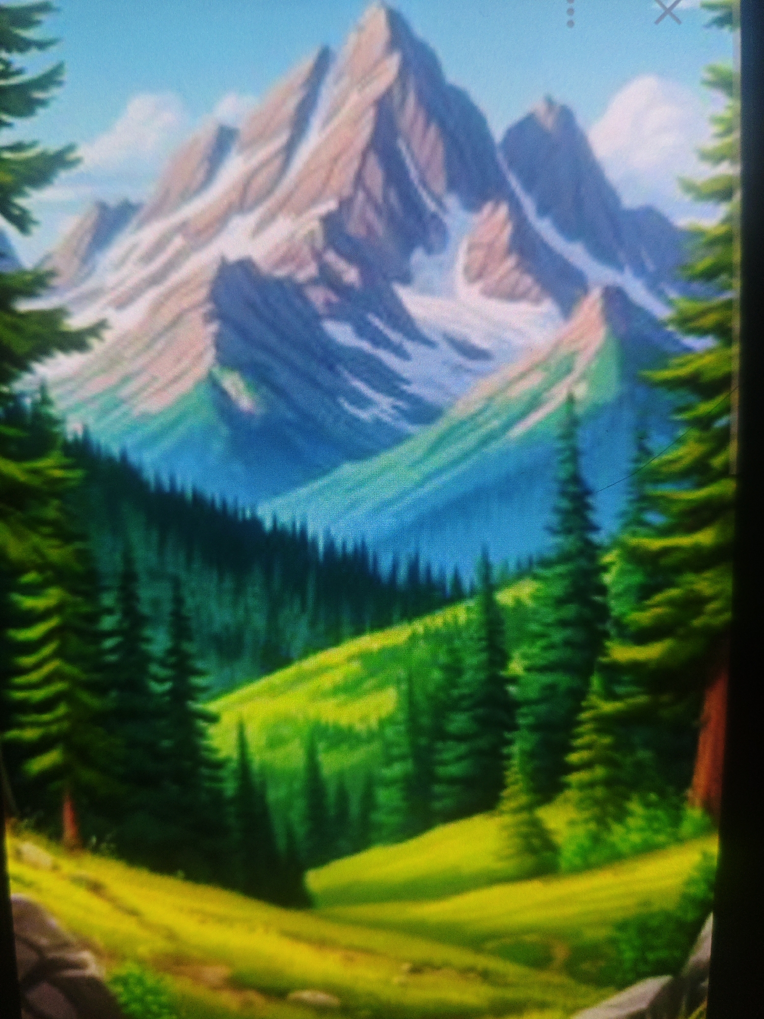The image depicts a vibrant, stylized landscape painting of a mountain range. The mountains are tall and jagged, with snow-capped peaks in shades of white, pink, and purple. Below the mountains, rolling green hills are dotted with dark green evergreen trees. In the foreground, a sunlit meadow is rendered in bright yellows and greens, with large rocks in the lower left corner. The scene is characterized by bold colors and a somewhat impressionistic style, creating a picturesque and serene natural environment. There are no people, animals, or man-made structures visible in the painting. The image has a slightly grainy texture, possibly due to the display it is being viewed on or the photographic reproduction of the artwork. The location in Armavir, Russia is not depicted in this image.