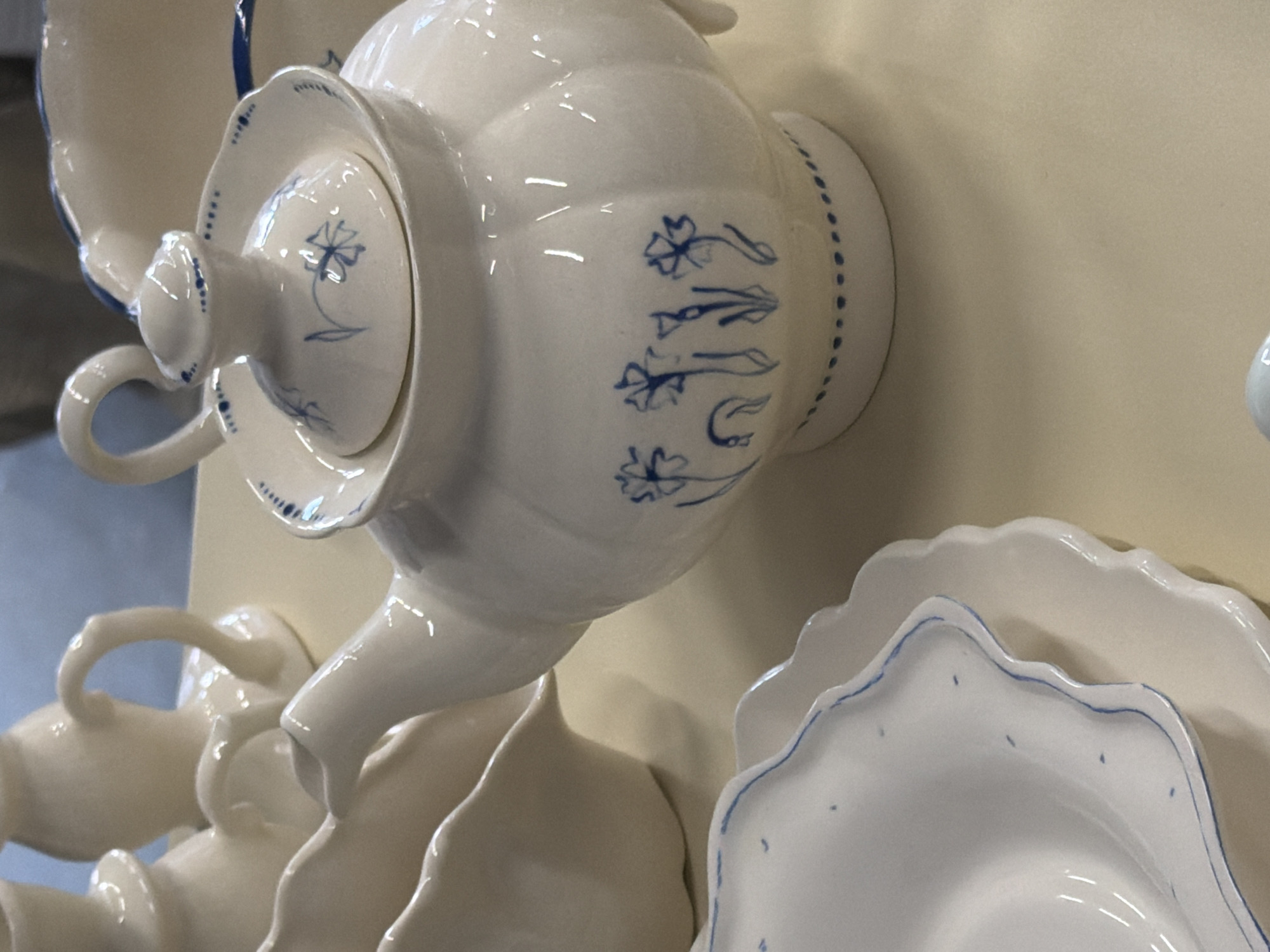 Close-up of a set of white porcelain tea set with blue floral decorations in the style of Russian Gzhel pottery. The tea set includes a teapot with a lid, cups, and saucers. The items appear to be stacked or arranged for display on a surface. The environment suggests an indoor setting, perhaps a museum, shop, or private collection. The specific location in Saint Petersburg, Russia, is unknown. No people are visible in the scene.