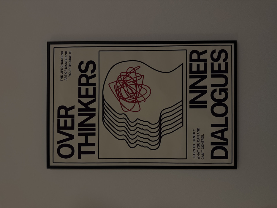 The image displays a framed poster with the title "Over Thinkers Inner Dialogues." The subtitle reads "The Life Changing Art of Mastering Your Thoughts" and "Learn to Identify What You Can and Can't Control." The artwork features a stylized profile of a head composed of layered, wavy lines. A red, scribbled mass fills the interior of the head shape. The poster has a cream-colored background and bold, black typography.