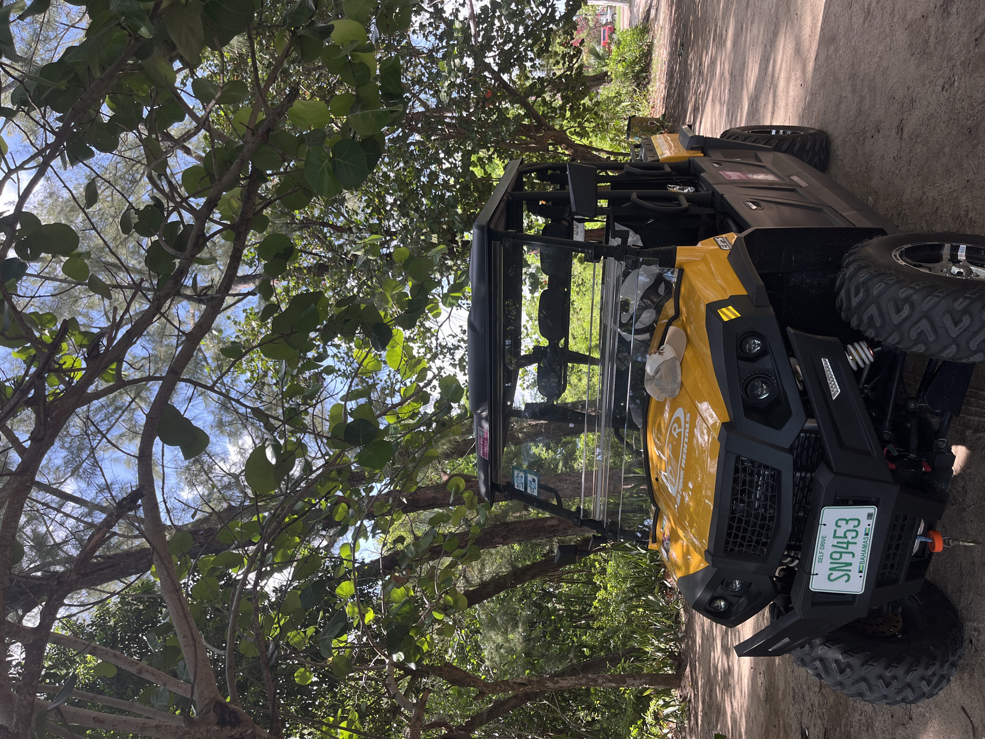 A UTV with the license plate "SN9453" parked under a tree, on a dirt ground. The location is Unknown, Unknown.